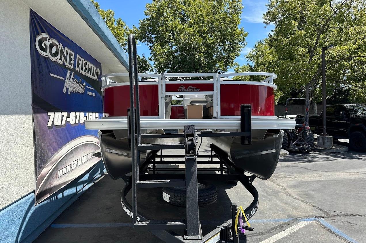 2026 Sun Tracker Bass Buggy 16 XL Select pontoon boat on trailer at dealership.