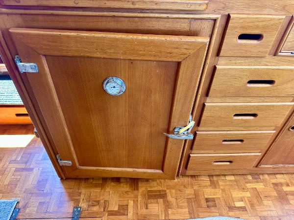 Wooden cabinetry inside a 1994 Grand Banks 42 Classic boat, featuring drawers and a door.