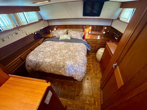 Cozy bedroom in 1994 Grand Banks 42 Classic yacht with wood paneling and double bed.
