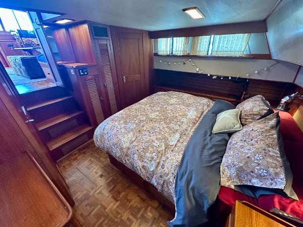 Cozy bedroom interior of 1994 Grand Banks 42 Classic yacht with wooden accents and patterned bedding.