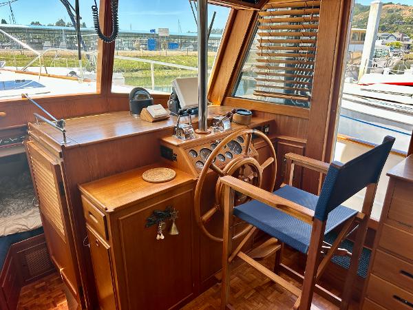 Interior helm of 1994 Grand Banks 42 Classic yacht with wooden steering wheel and chair.