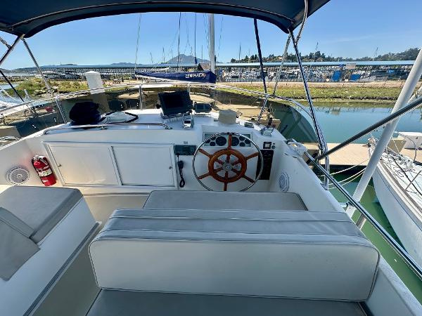 1994 Grand Banks 42 Classic yacht helm with wooden wheel and seating, docked at marina.