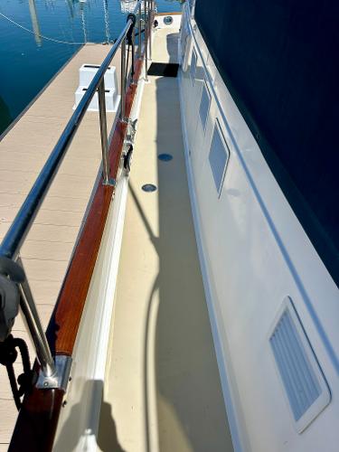 Side deck of a 1994 Grand Banks 42 Classic yacht with wooden railings.