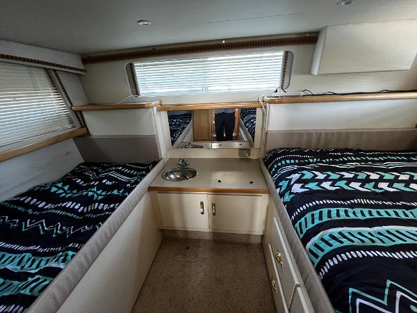 1996 Carver 325 Aft Cabin interior with twin beds and compact kitchenette.