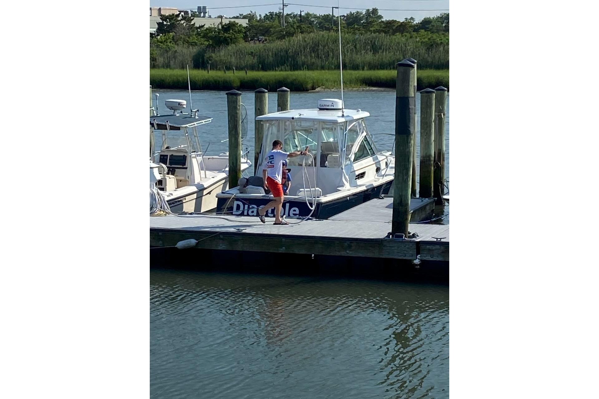 2006 Back Cove 26 boat docked with person on pier, surrounded by water and greenery.