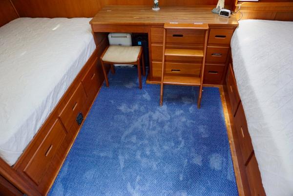 1982 Grand Banks Classic cabin with twin beds, wooden furniture, and blue carpet.