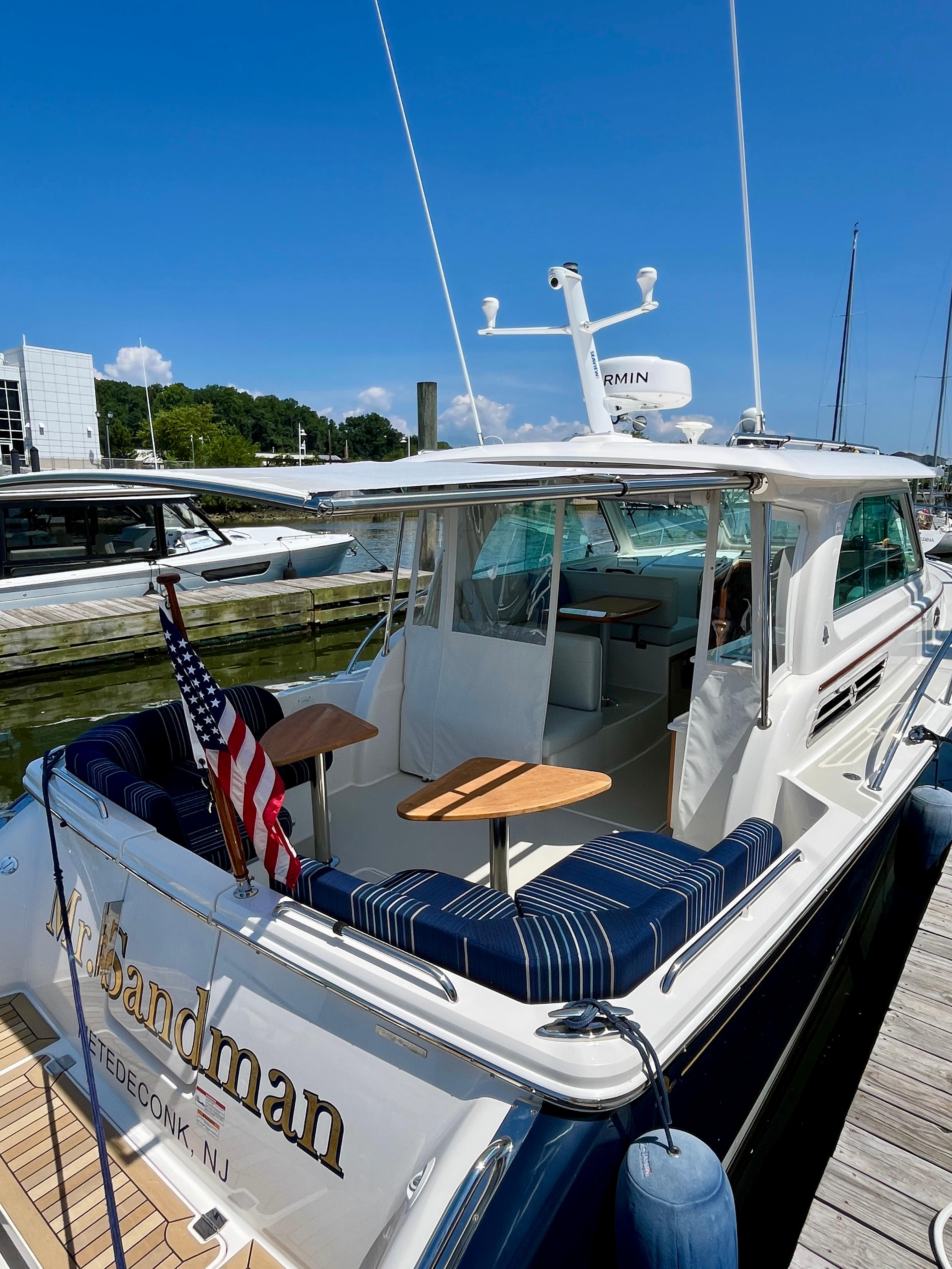 2023 Back Cove 34O yacht docked, featuring a spacious deck with seating and an American flag.