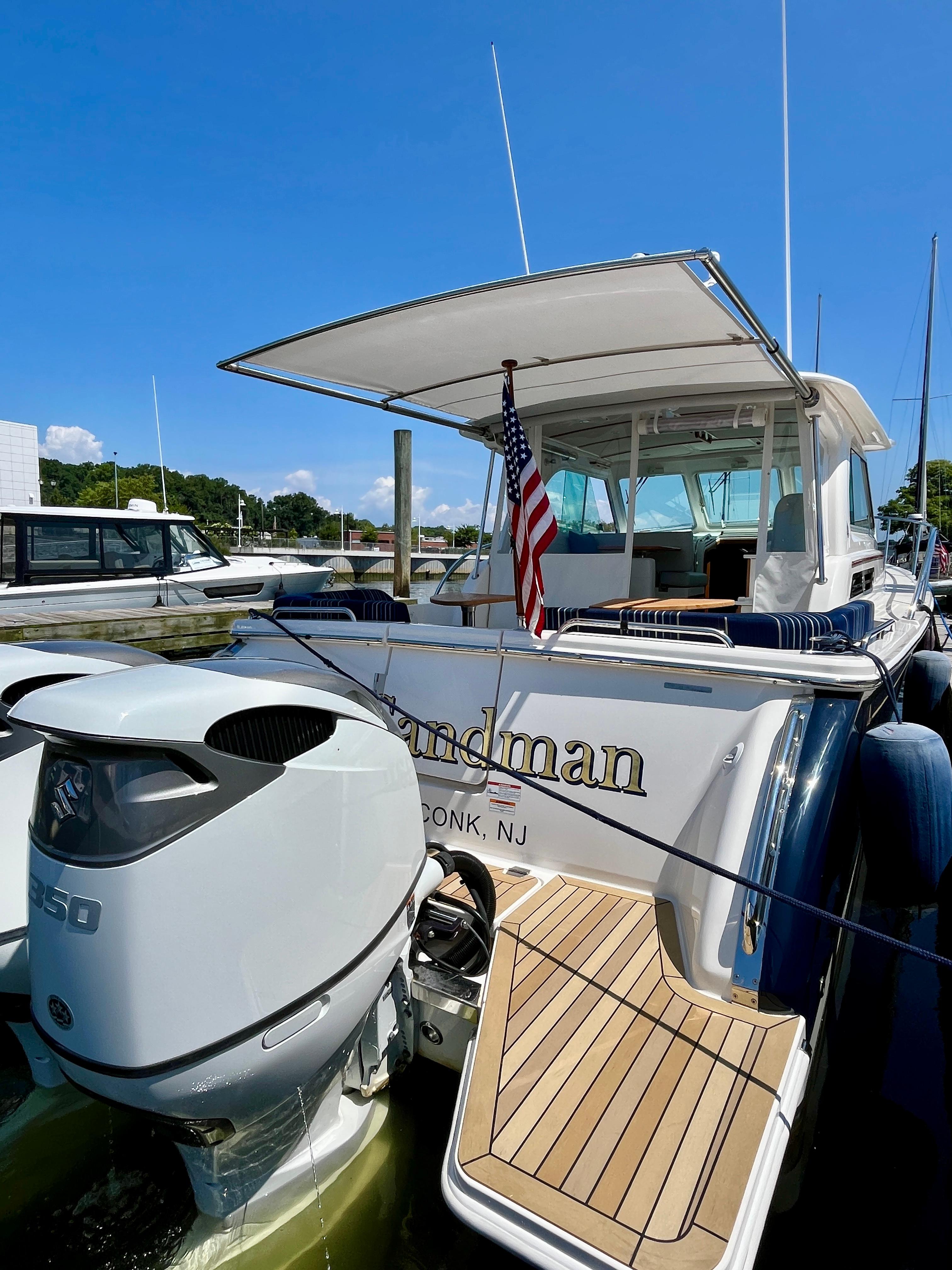 2023 Back Cove 34O yacht docked, featuring outboard motor and American flag.