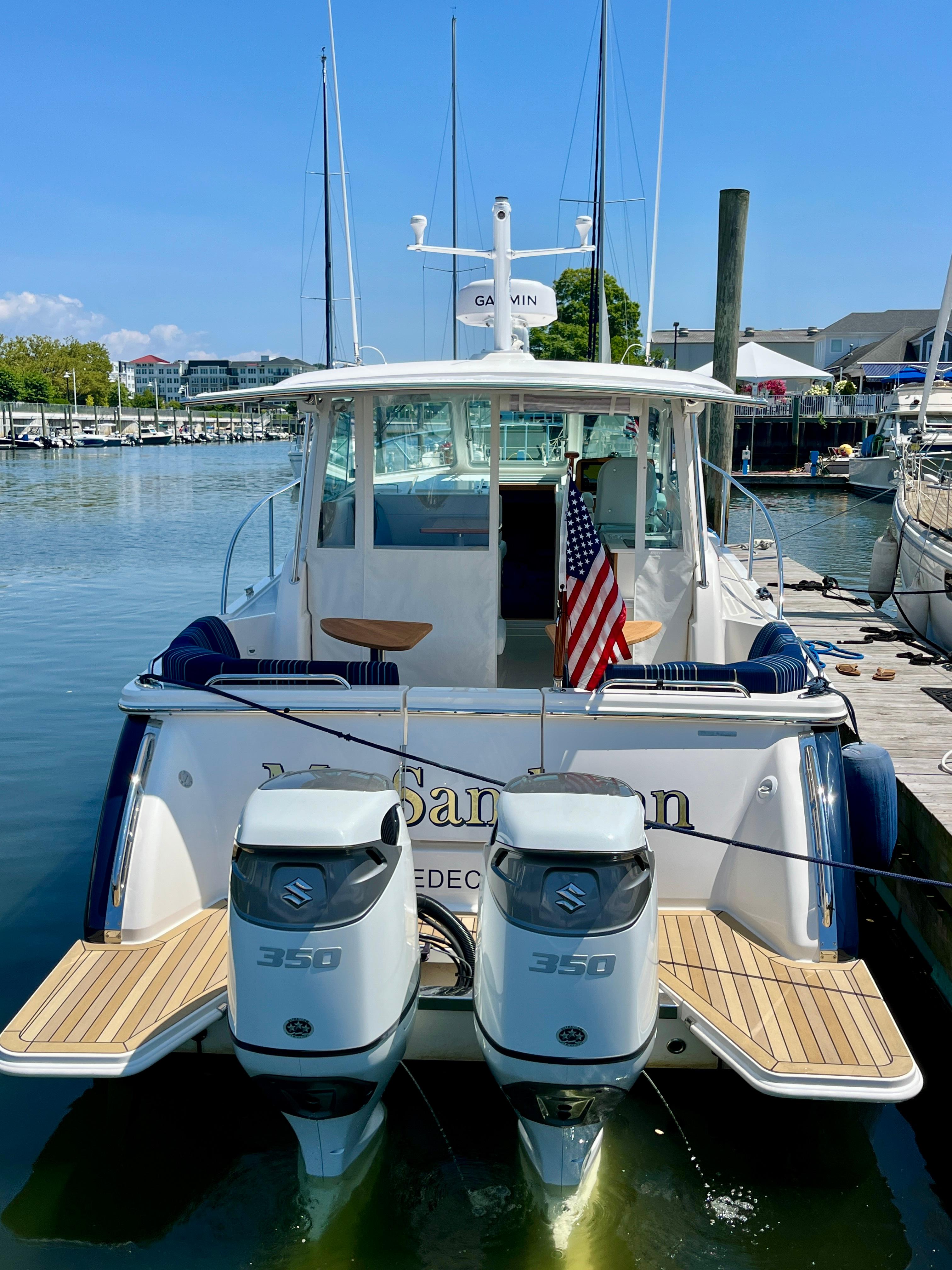 2023 Back Cove 34O boat docked with dual Suzuki 350 engines and American flag.