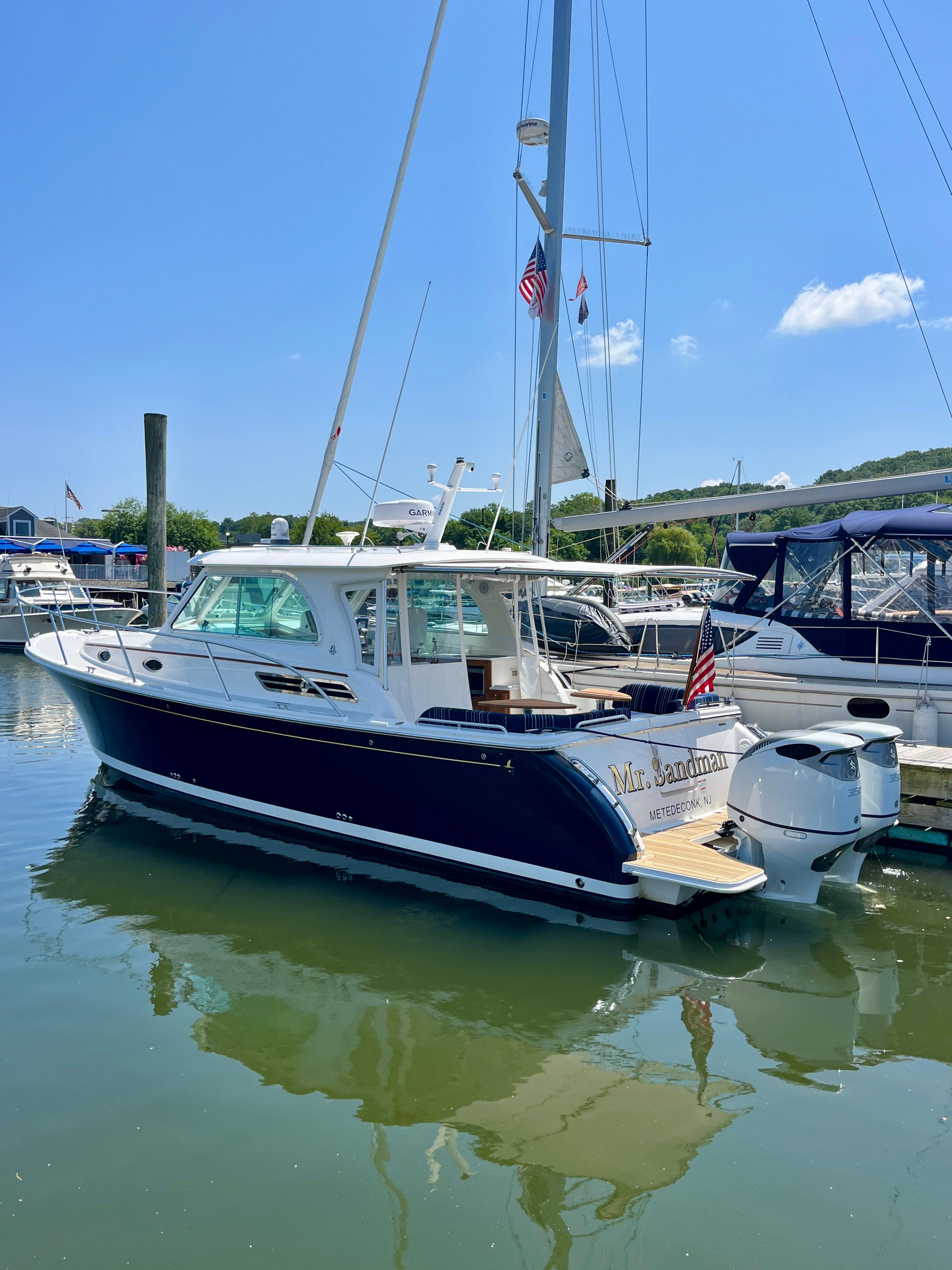 2023 Back Cove 34O boat docked in a marina under a clear blue sky.