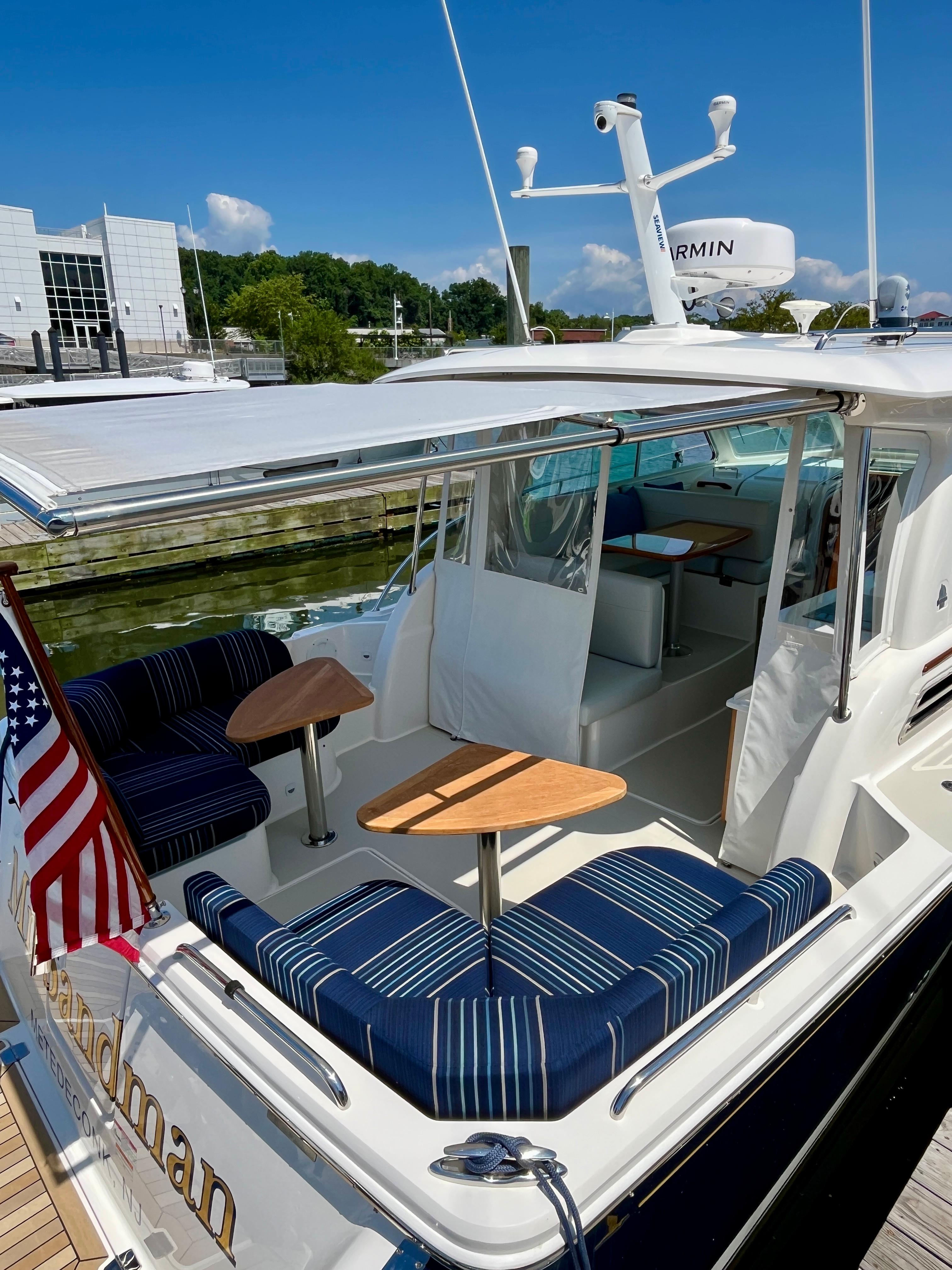 2023 Back Cove 34O yacht with striped seating and American flag, docked under clear skies.
