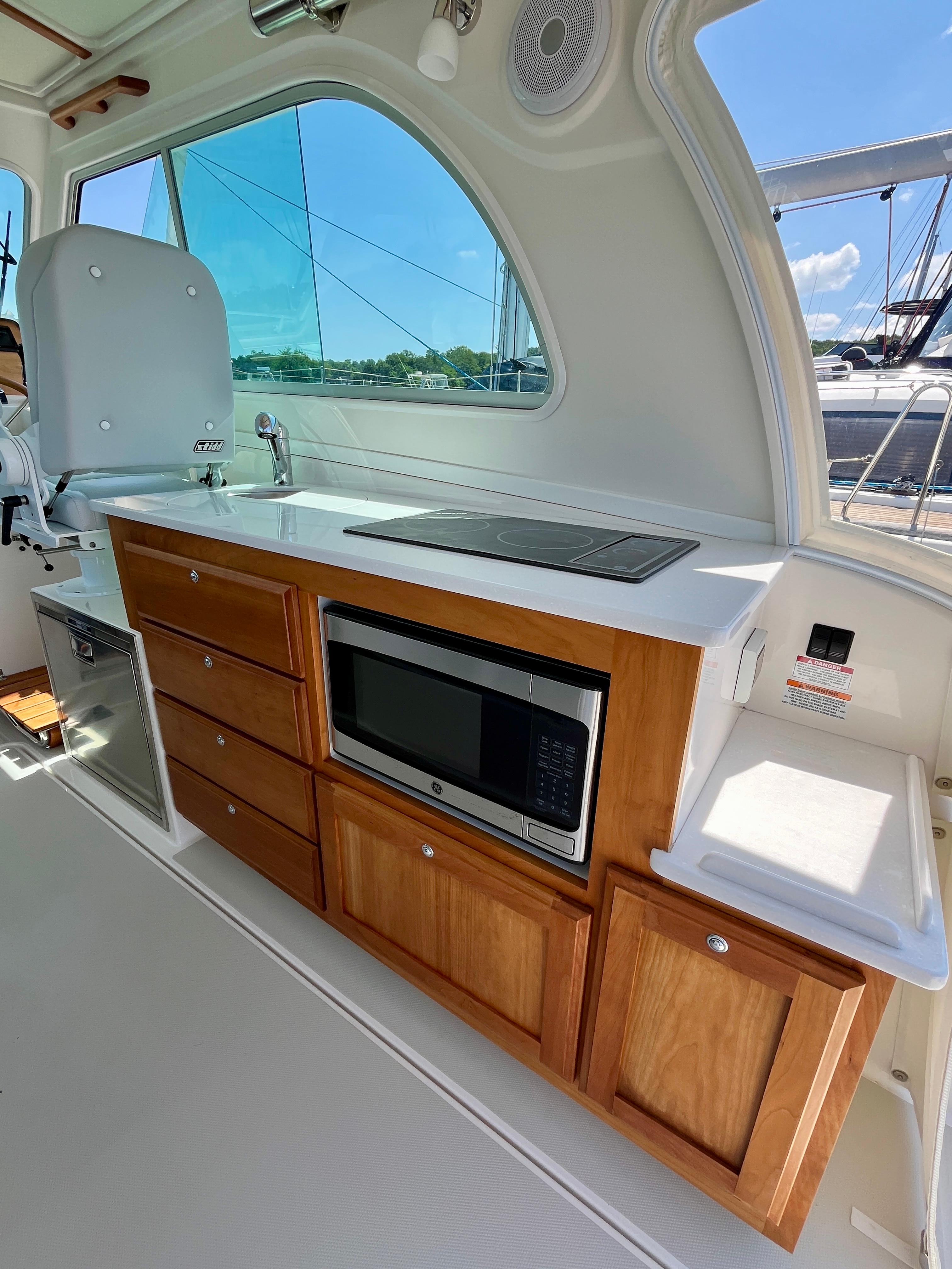 2023 Back Cove 34O yacht interior with kitchenette, featuring wooden cabinets and modern appliances.
