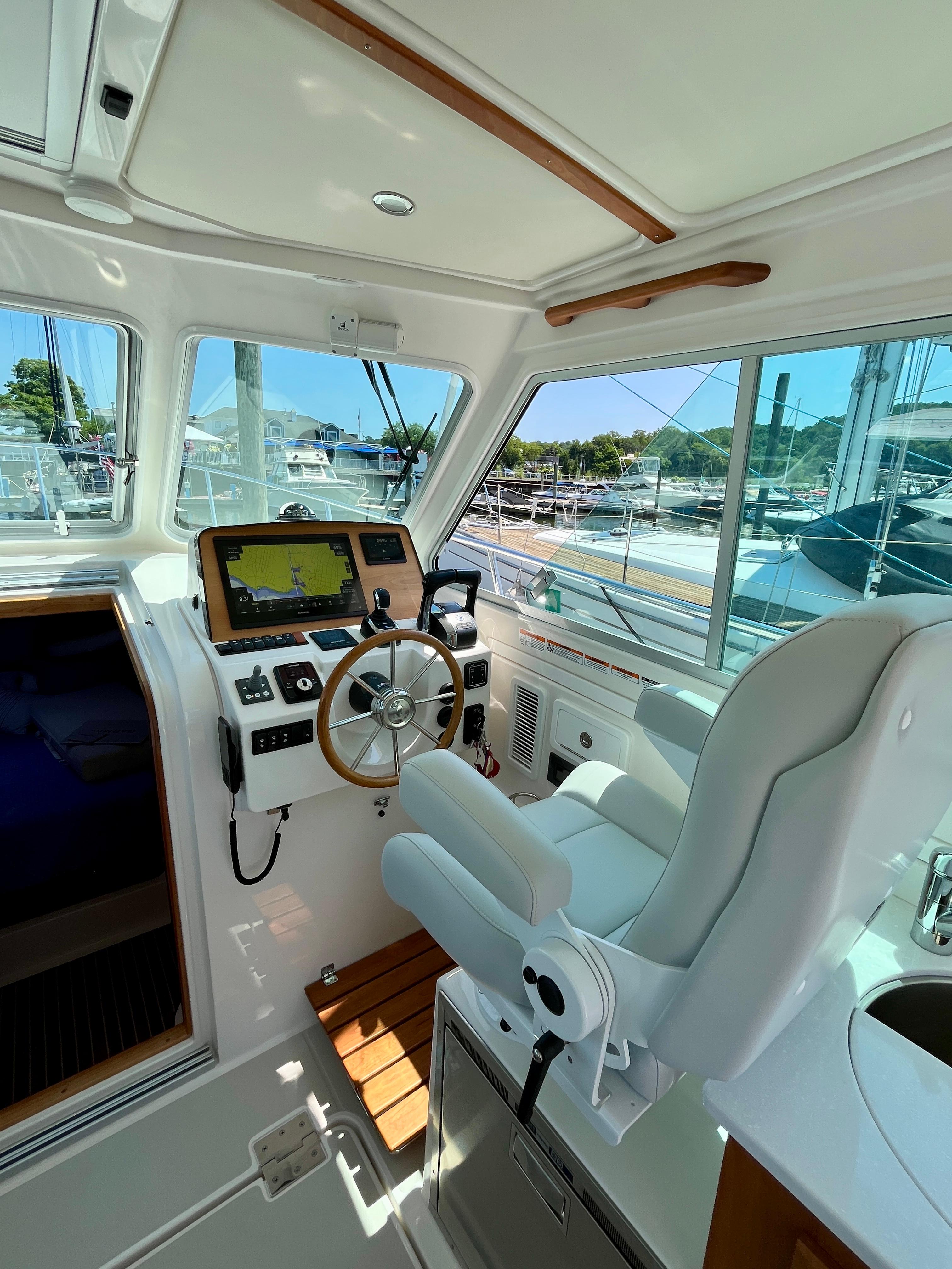 2023 Back Cove 34O helm with modern controls and comfortable seating in a marina setting.