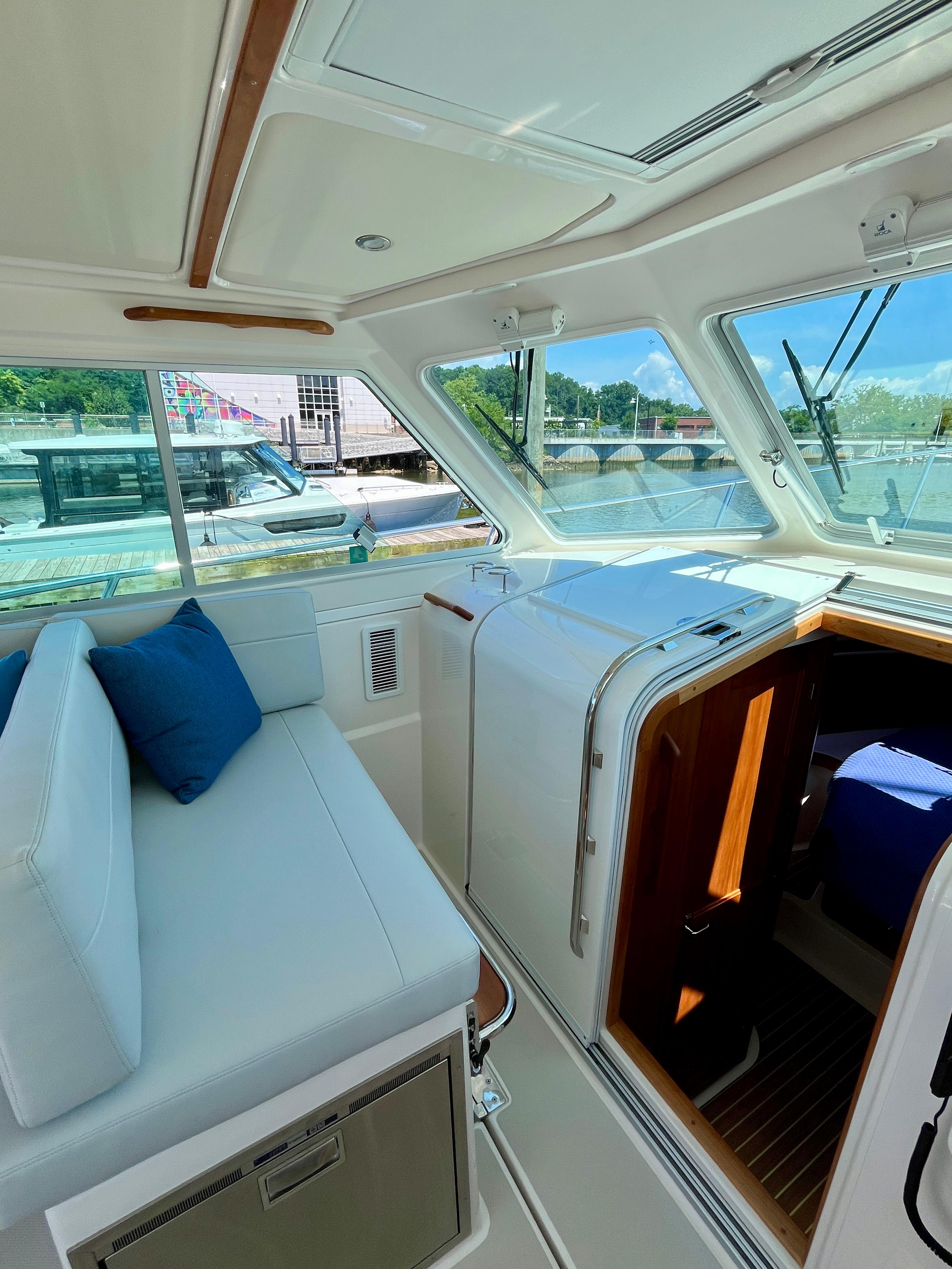 Interior of 2023 Back Cove 34O yacht with white seating and blue cushions.