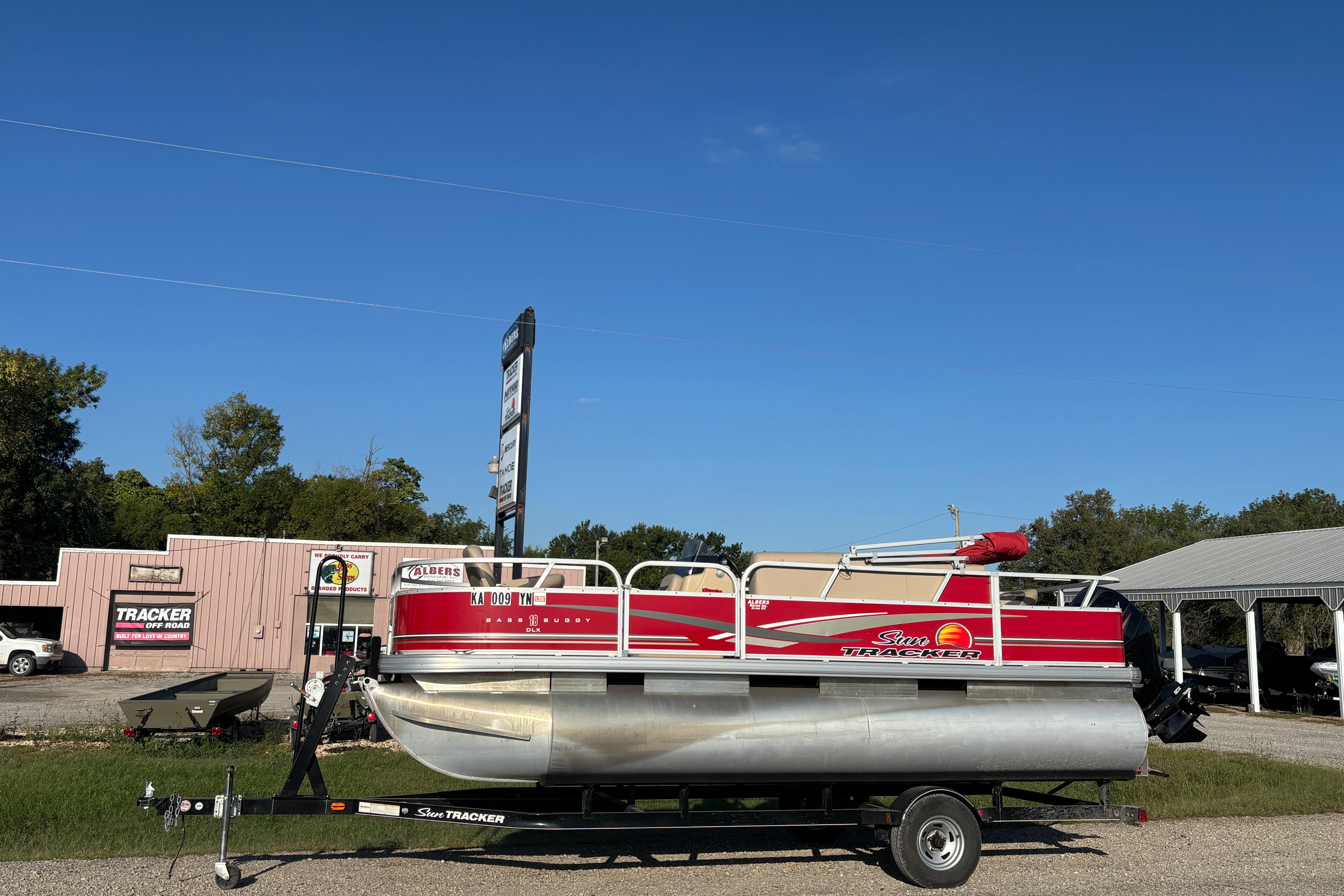 2014 Sun Tracker Bass Buggy 18 DLX pontoon boat on trailer, dealership background.