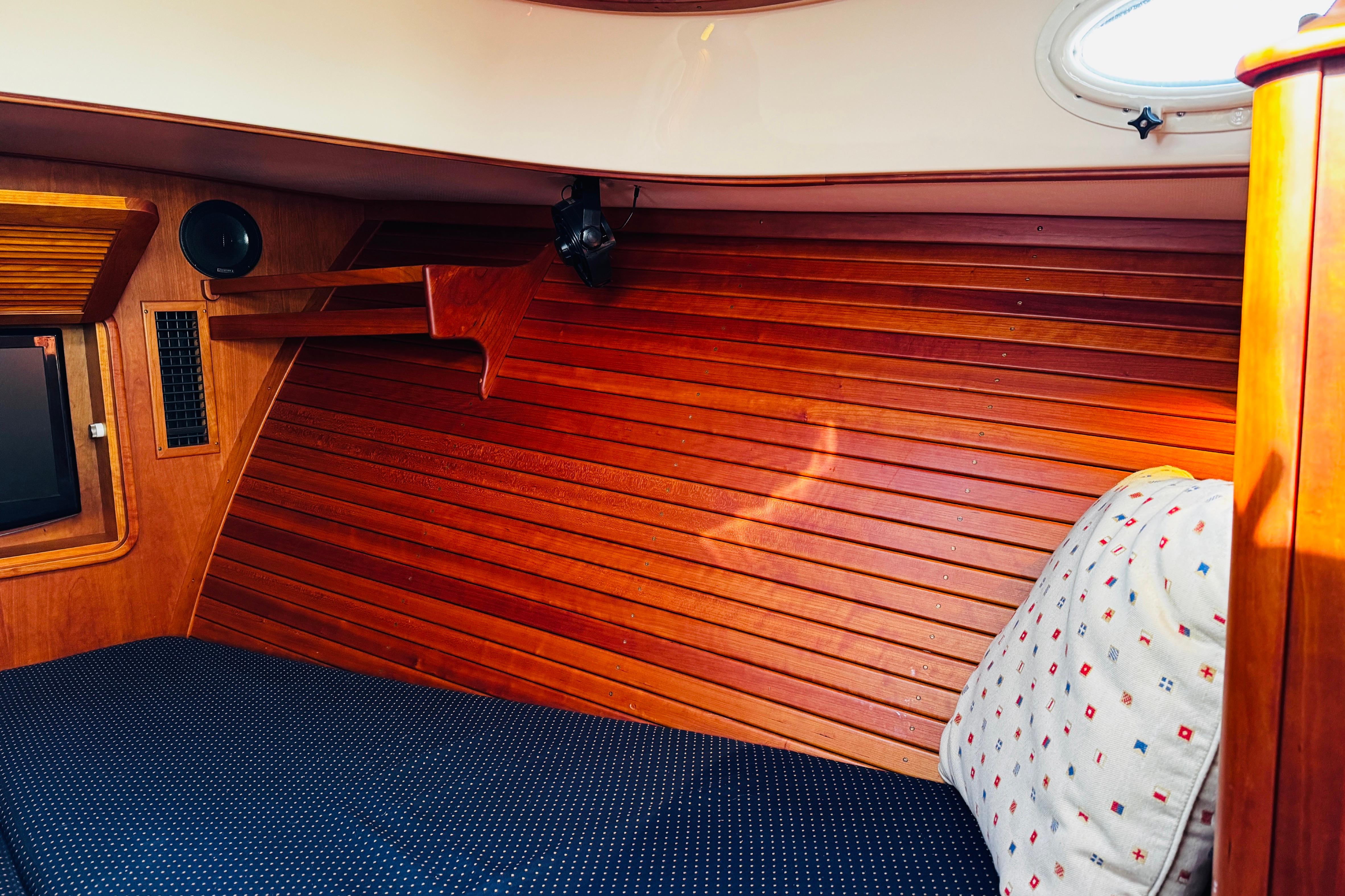 2012 Hinckley Picnic Boat MKIII cabin interior with wooden paneling and cozy bedding.