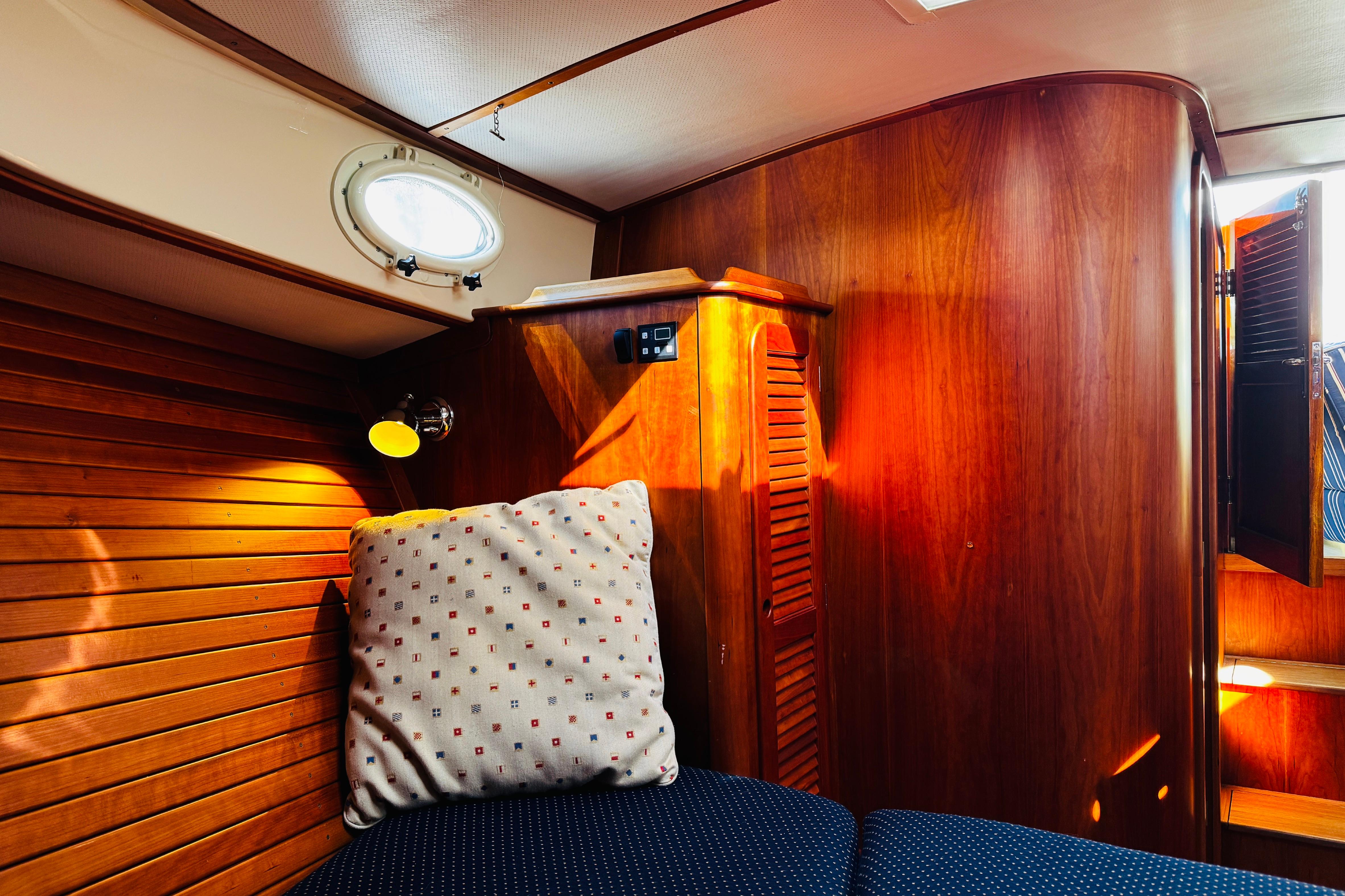 Cozy cabin interior of 2012 Hinckley Picnic Boat MKIII with wooden paneling and cushion.