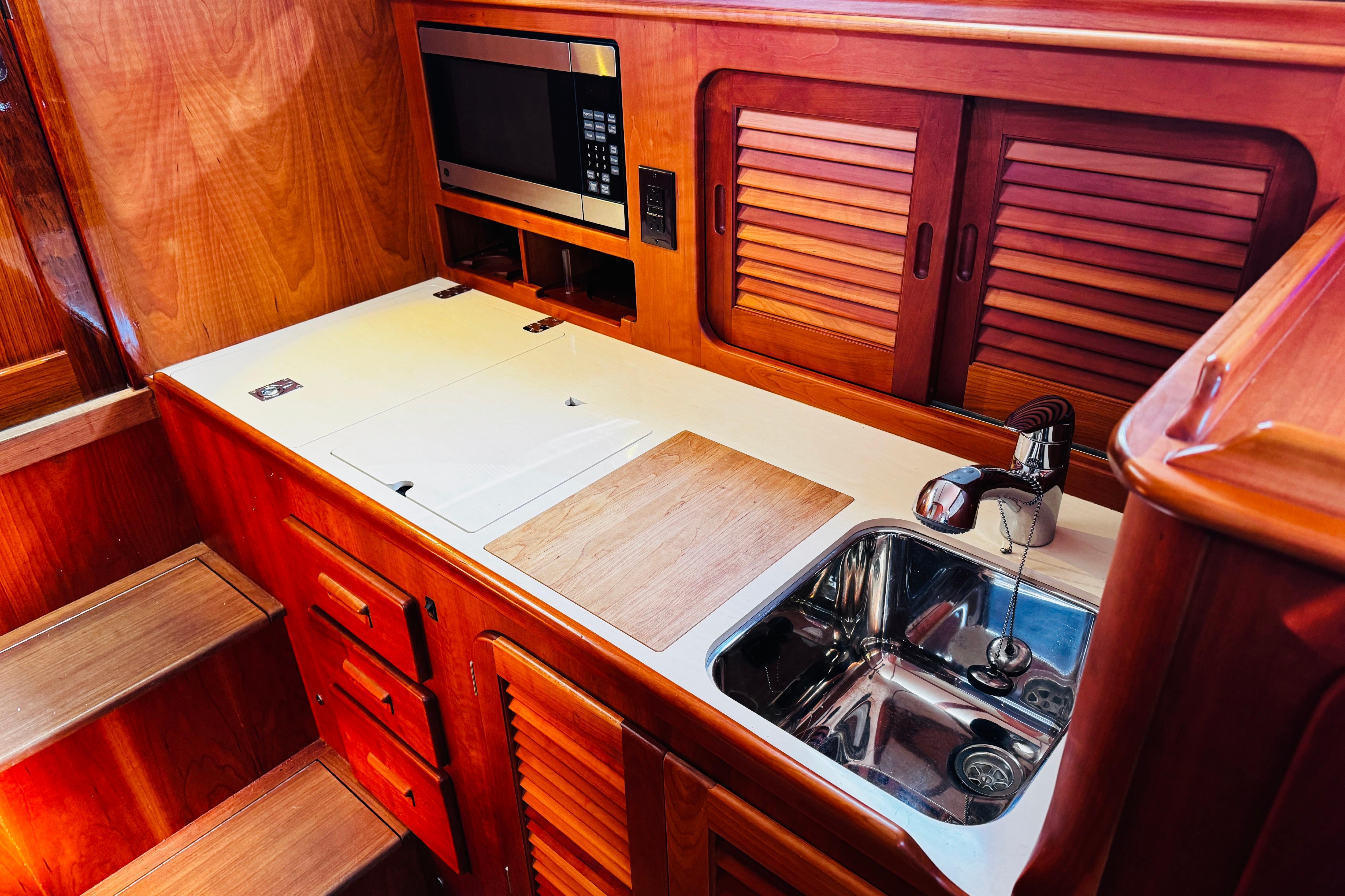 Hinckley Picnic Boat MKIII 2012 interior kitchen with wooden cabinetry and stainless steel sink.