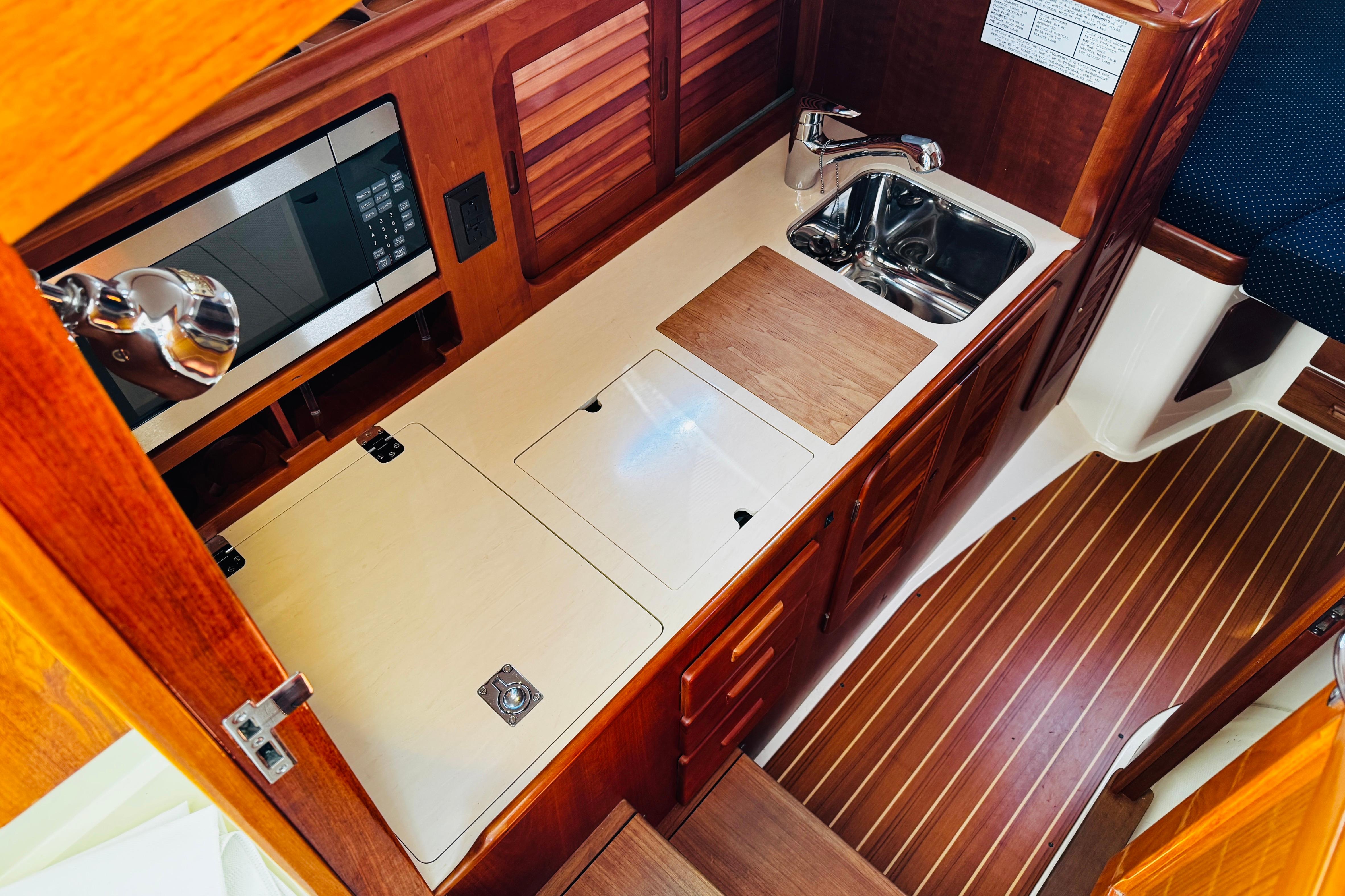 Hinckley Picnic Boat MKIII 2012 interior galley with wood cabinetry, sink, and microwave.