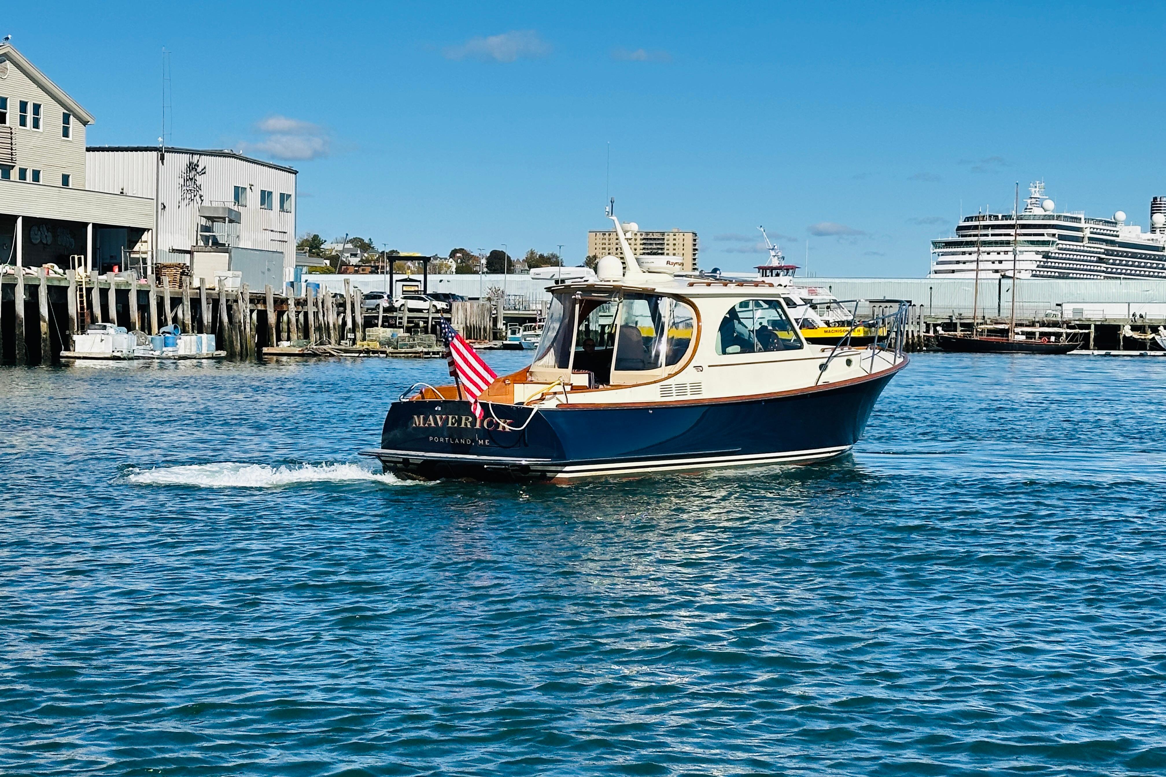 Hinckley Picnic Boat MKIII 2012 cruising in a harbor with buildings and a cruise ship.