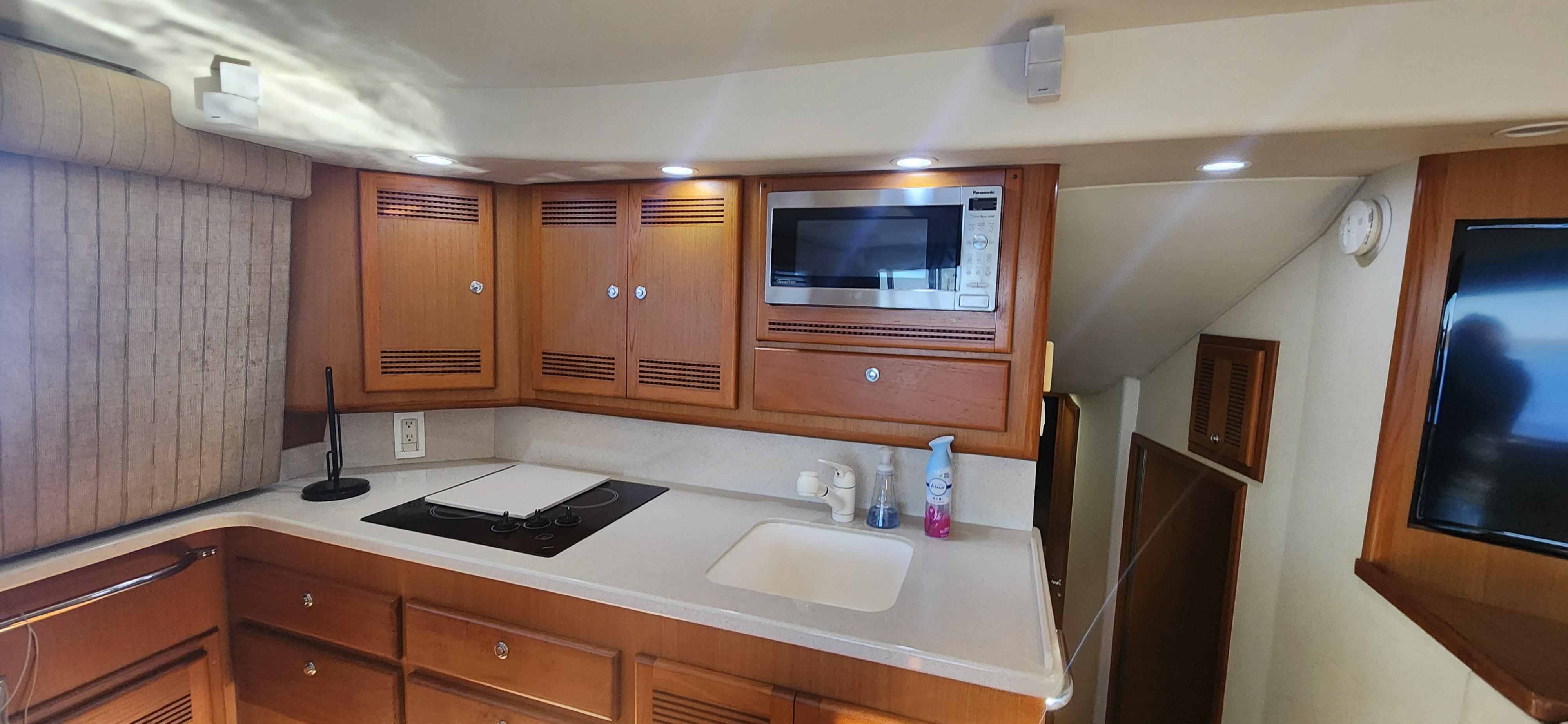 Cabo-48 Convertible 2004-Laura K AL-US-2004 Cabo 48 Convertible yacht kitchen with wooden cabinets, microwave, and countertop.-9710440 | Thumbnail