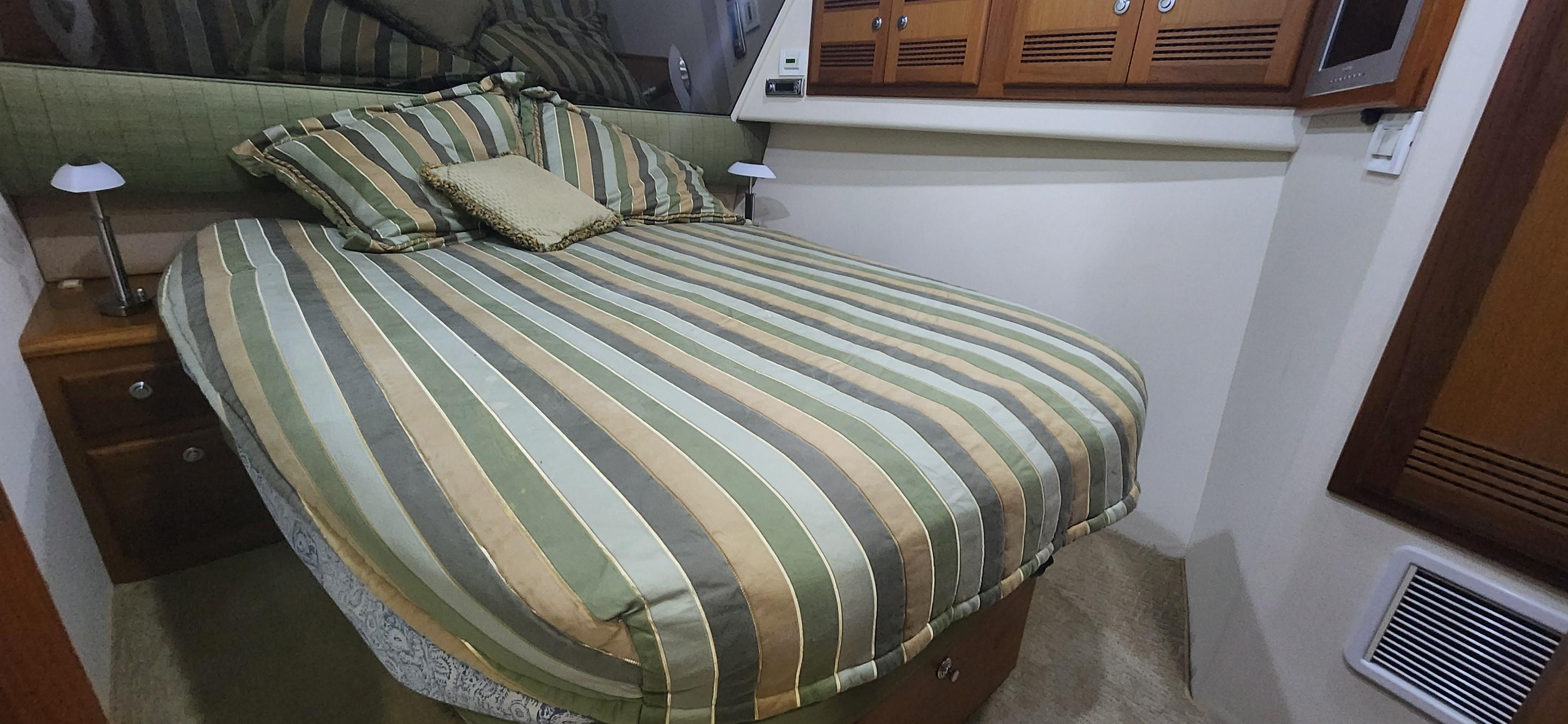 Cabo-48 Convertible 2004-Laura K AL-US-Cozy bedroom in 2004 Cabo 48 Convertible yacht with striped bedding and wooden cabinets.-9710440 | Thumbnail