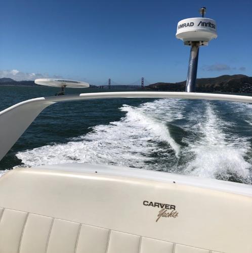 1997 Carver 350 Mariner cruising on open water with scenic bridge view.