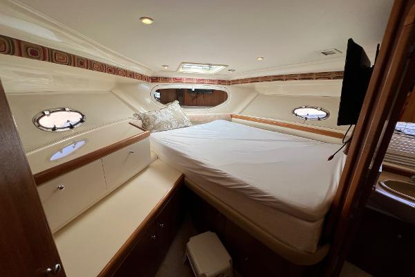 1997 Carver 350 Mariner cabin interior with bed, portholes, and storage cabinets.
