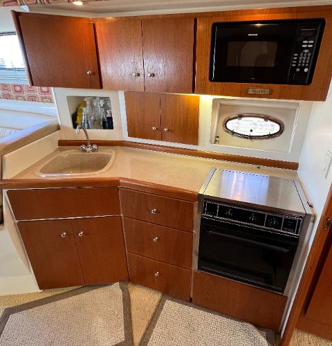 1997 Carver 350 Mariner kitchen with wood cabinets, sink, oven, and microwave.