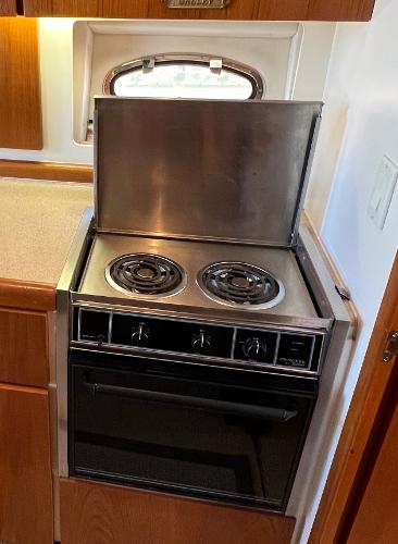 1997 Carver 350 Mariner kitchen with stove and oven, featuring wooden cabinetry.