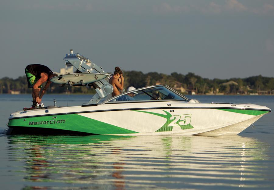 2013 MasterCraft X-25 boat on calm water with people onboard, featuring green and white design.