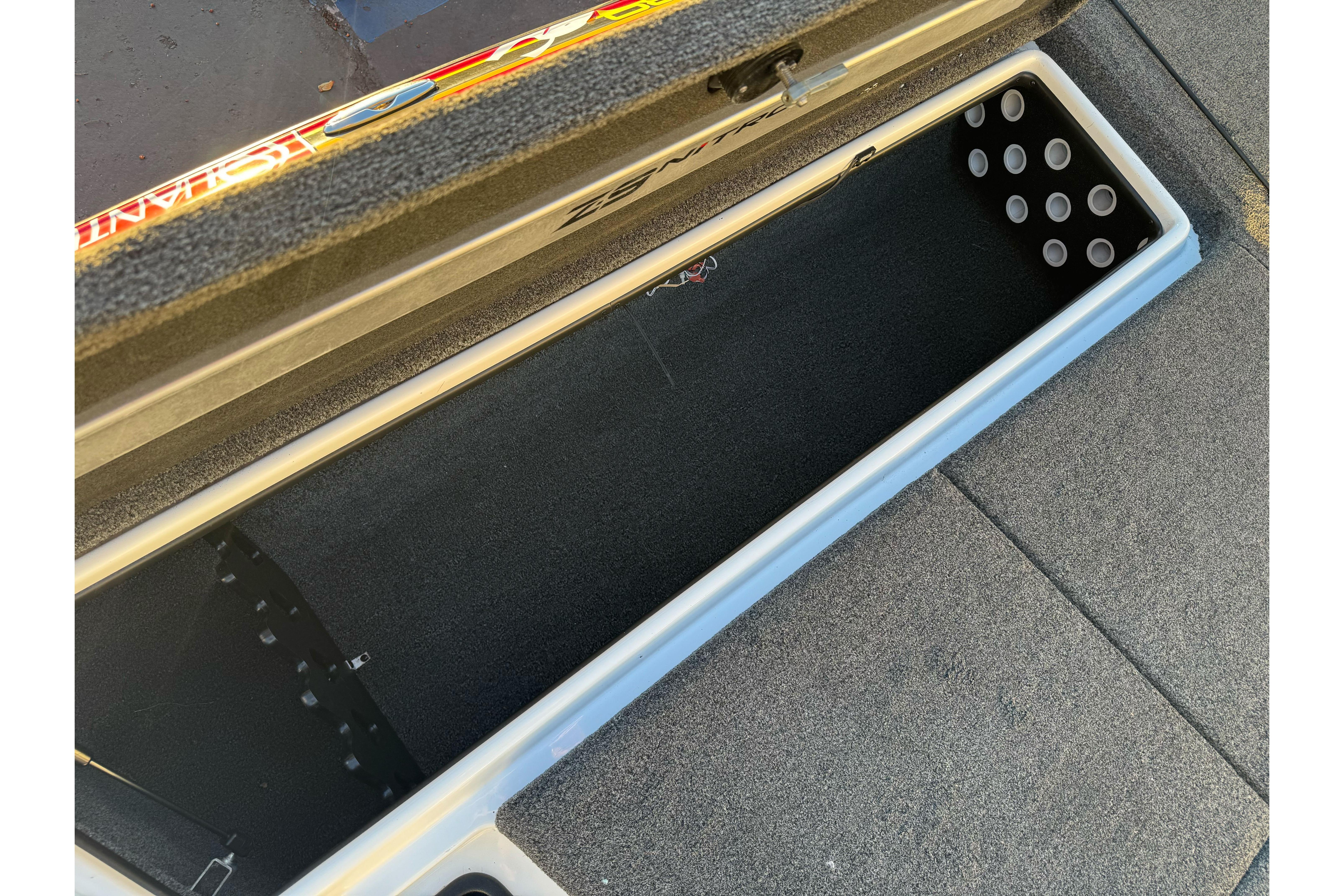 Open storage compartment of 2011 Nitro Z-9 DC boat, featuring carpeted interior and rod holders.