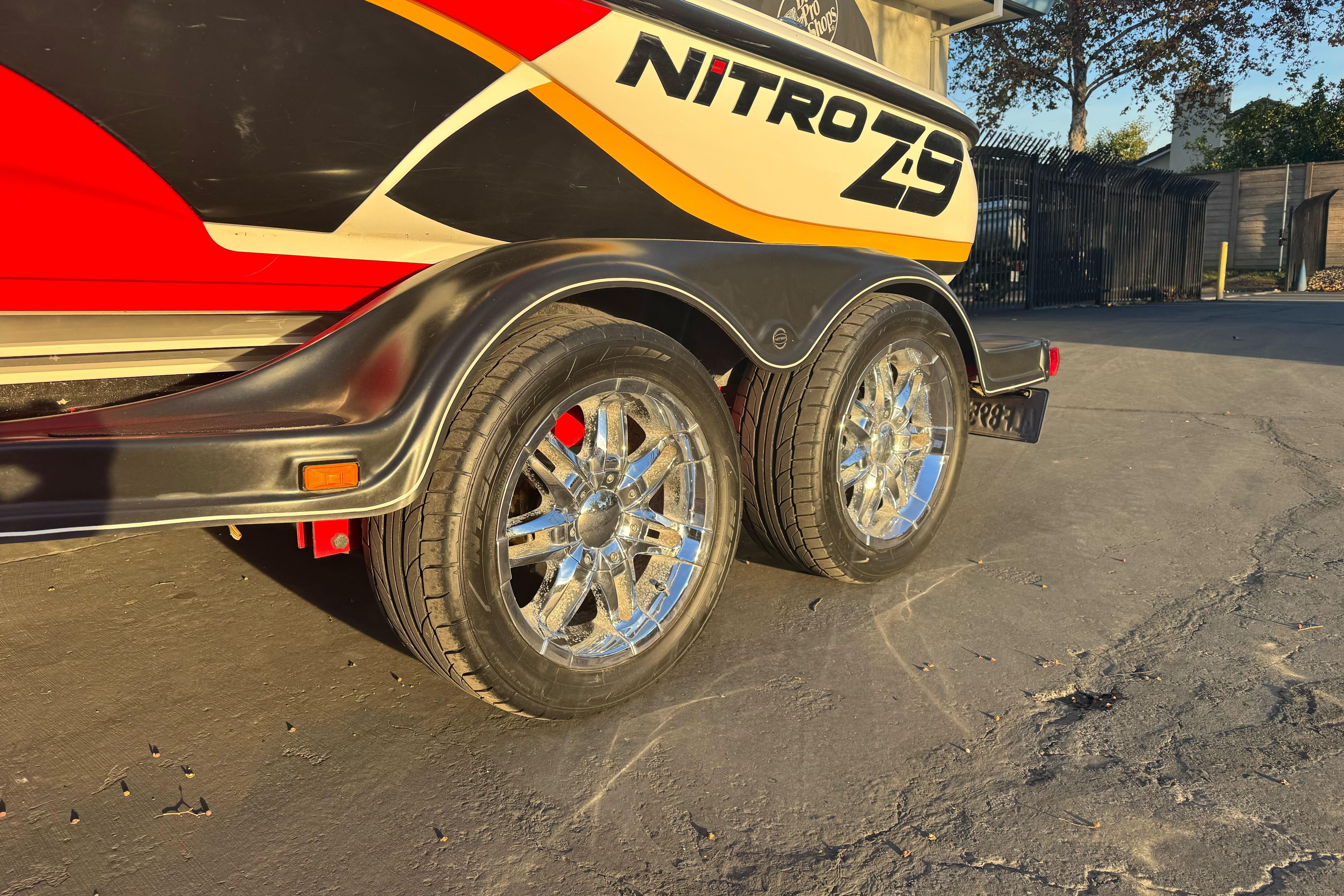 2011 Nitro Z-9 DC boat trailer with chrome wheels in a sunny outdoor setting.
