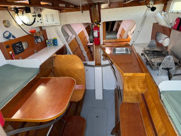 Interior of 1982 Greene Marine 35 Acapella sailboat with wooden furnishings and compact kitchen.