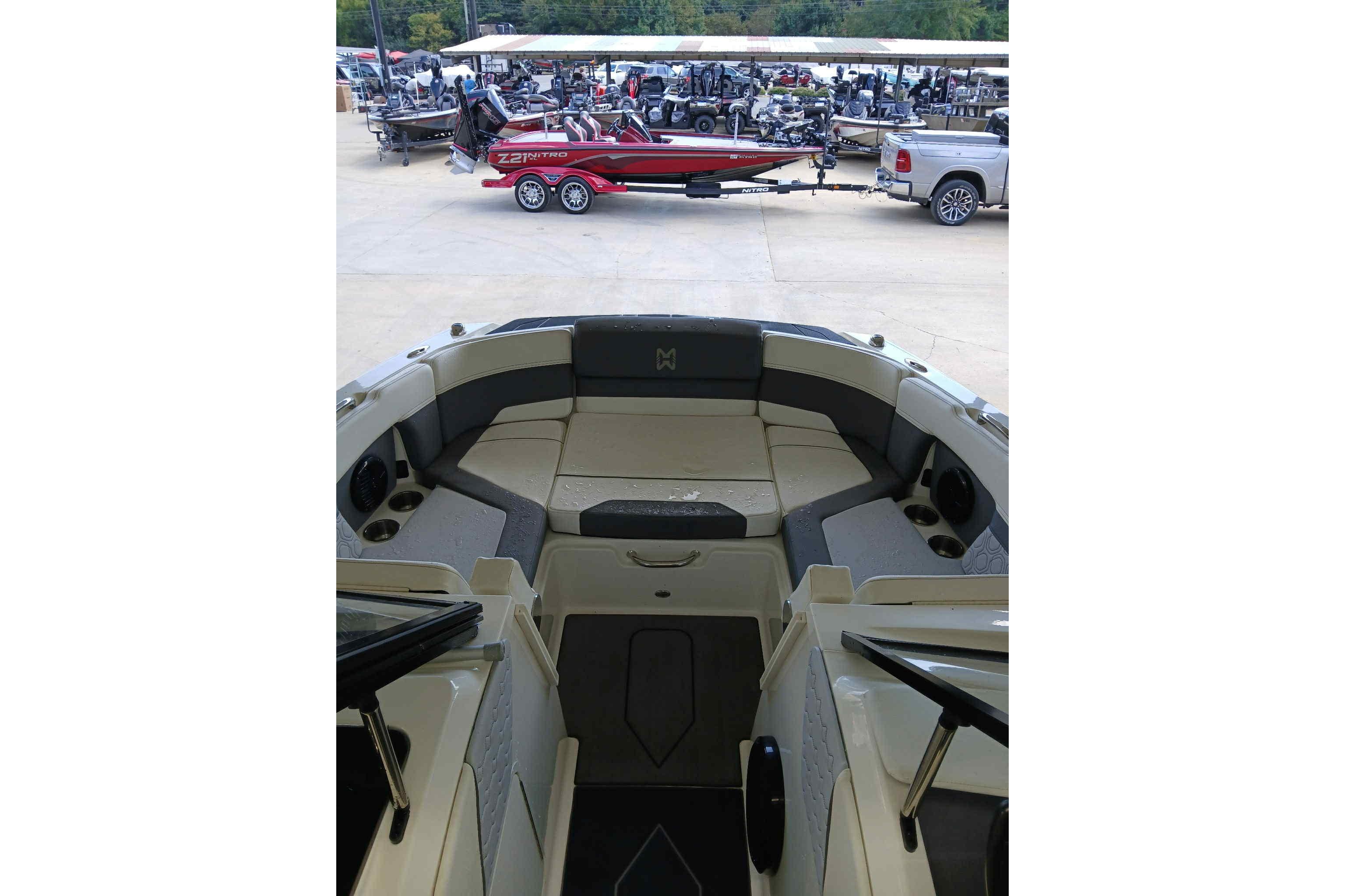 2023 Heyday H22 boat interior with seating, parked near a red boat and truck.