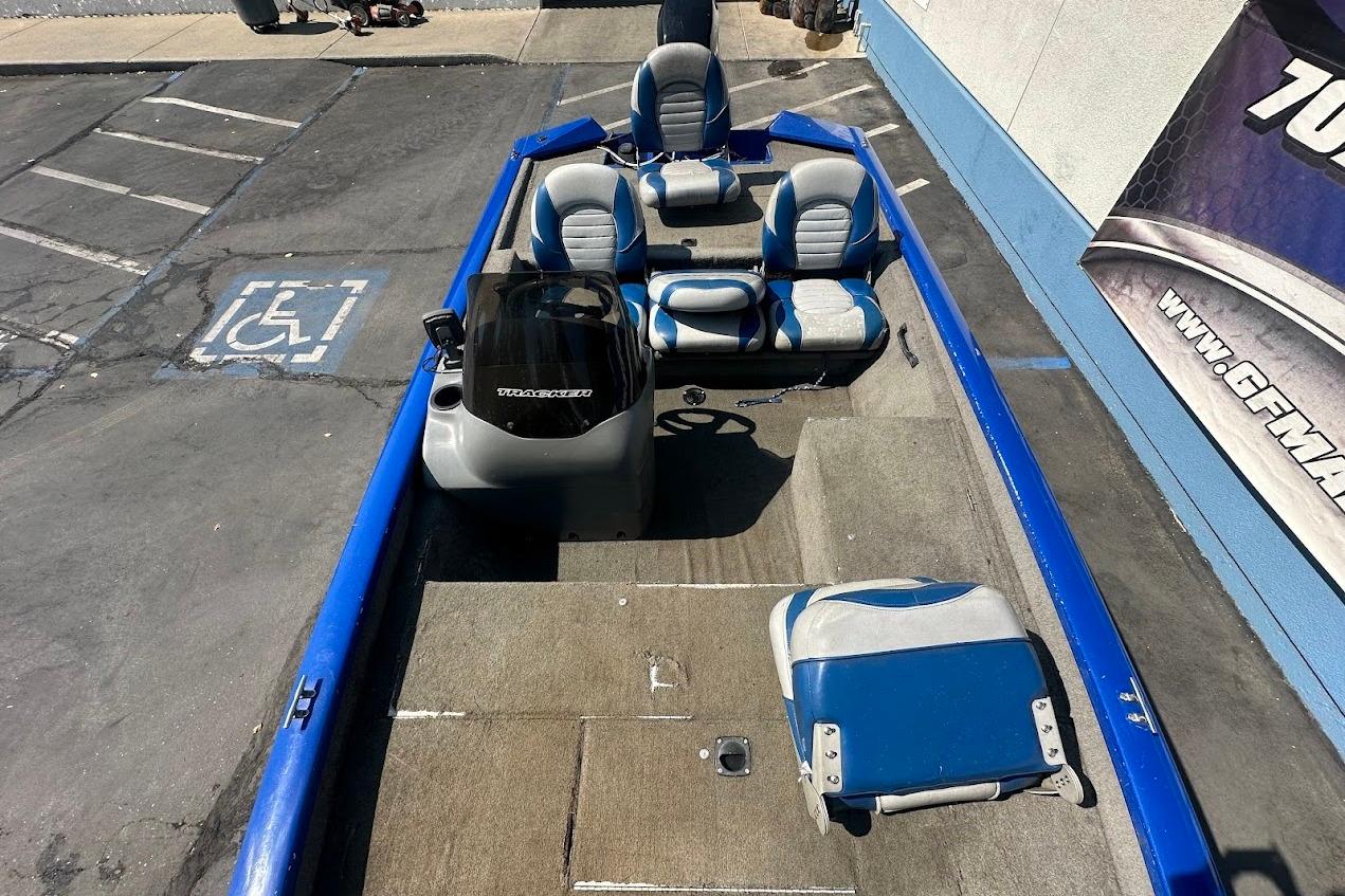 2005 Bass Tracker Pro Team 175 boat with blue and gray seating, parked on pavement.