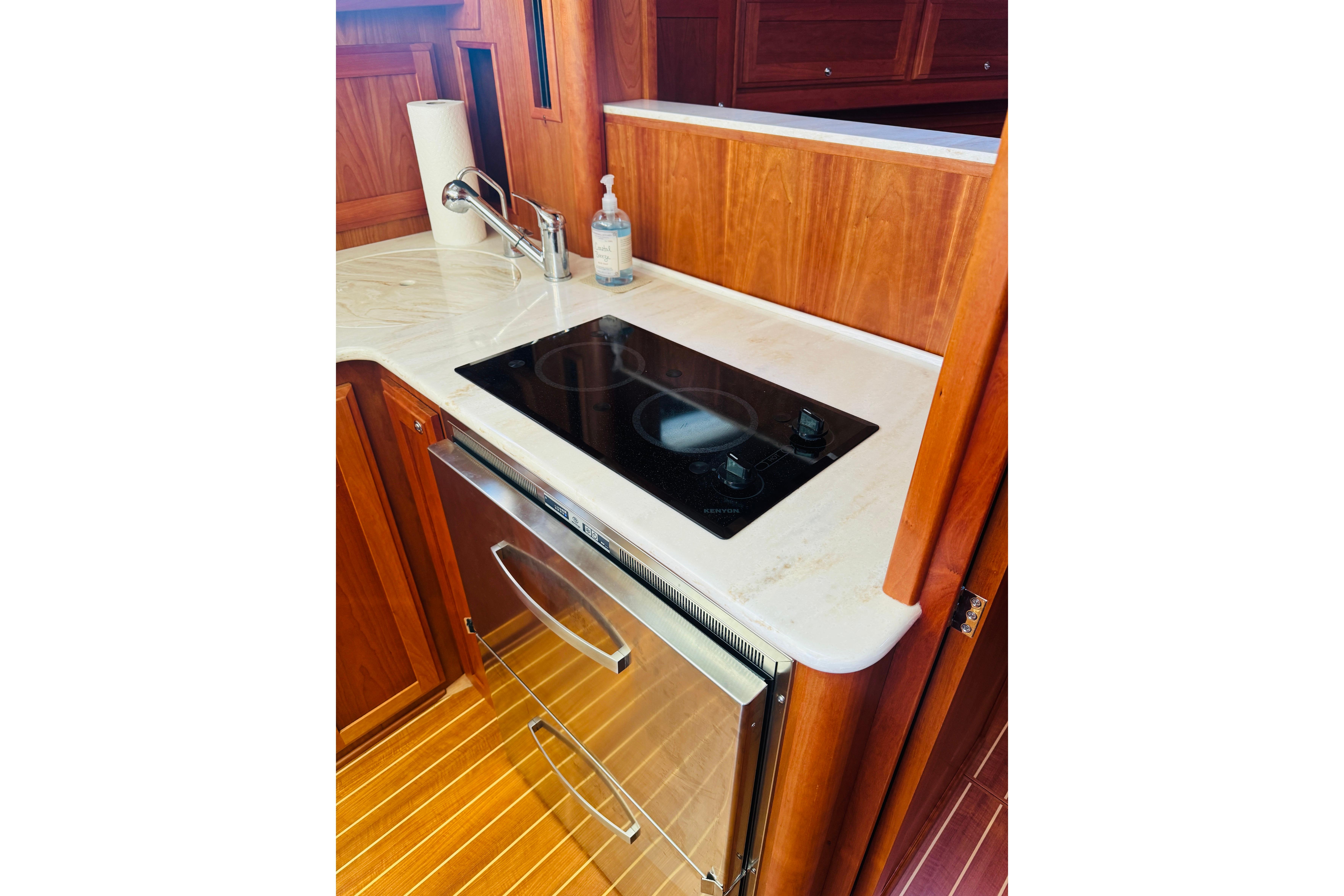 2015 Sabre 38 Salon Express kitchen with stove, sink, and wooden cabinetry.