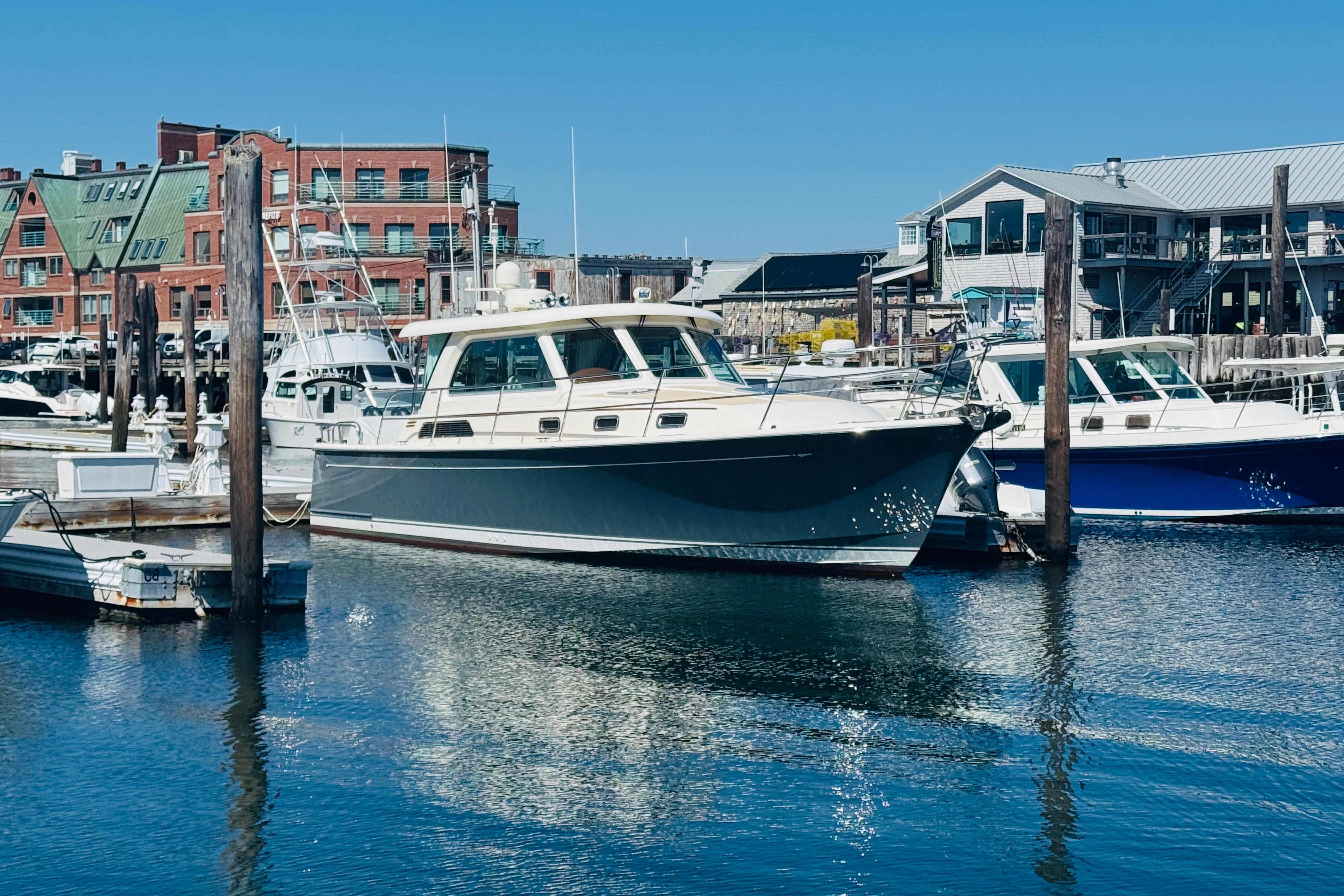 2015 Sabre 38 Salon Express yacht docked in a marina with waterfront buildings.