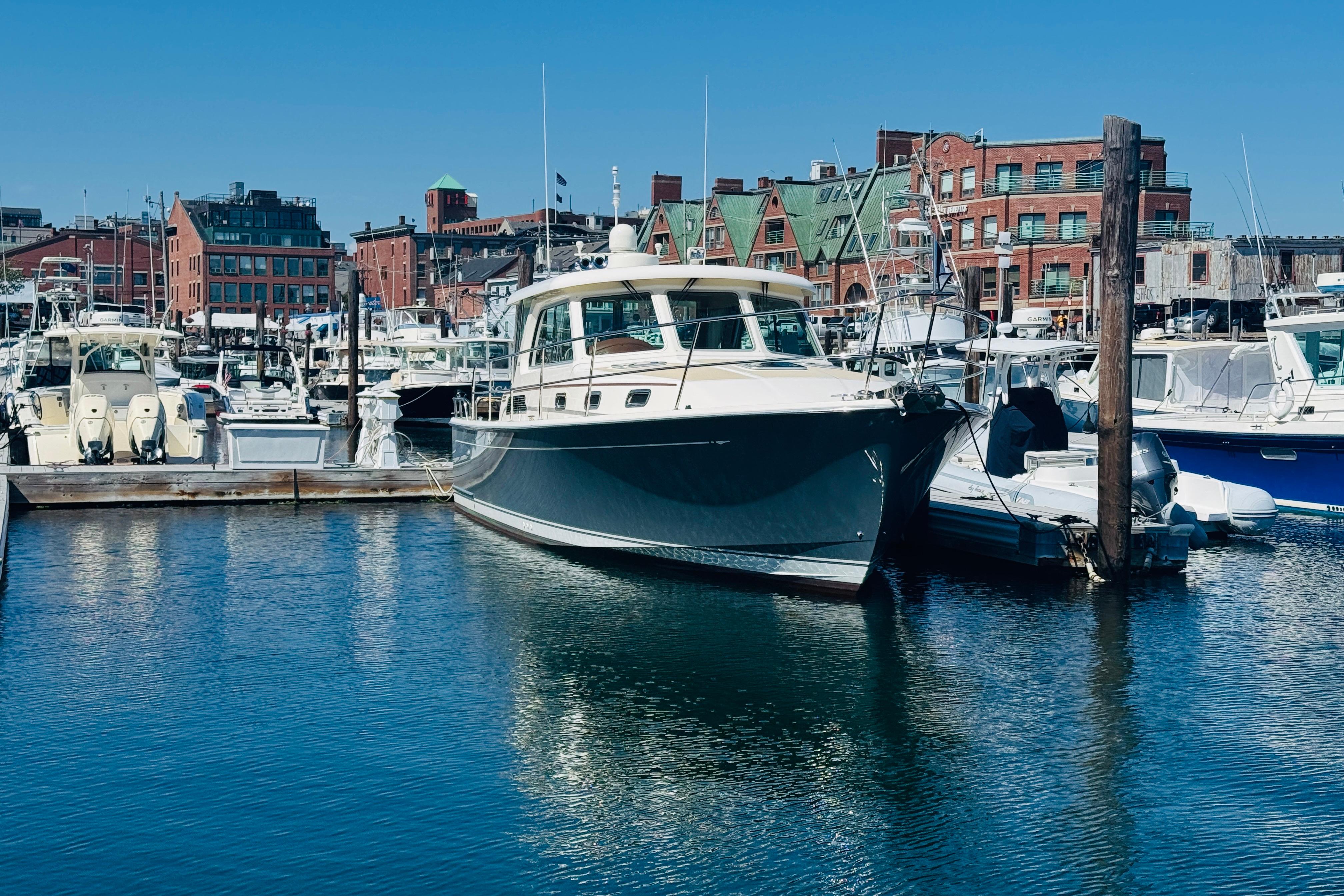 2015 Sabre 38 Salon Express yacht docked in a bustling marina with cityscape backdrop.