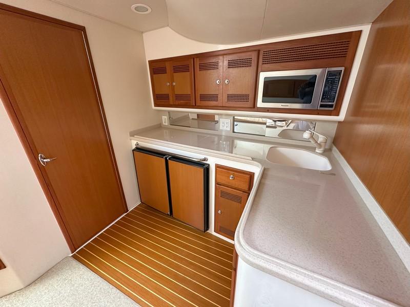 Cabo-Express 2004-TUNA DAZE MA-US-2004 Cabo Express yacht kitchen with wood cabinets, microwave, and compact fridge.-5384122 | Thumbnail
