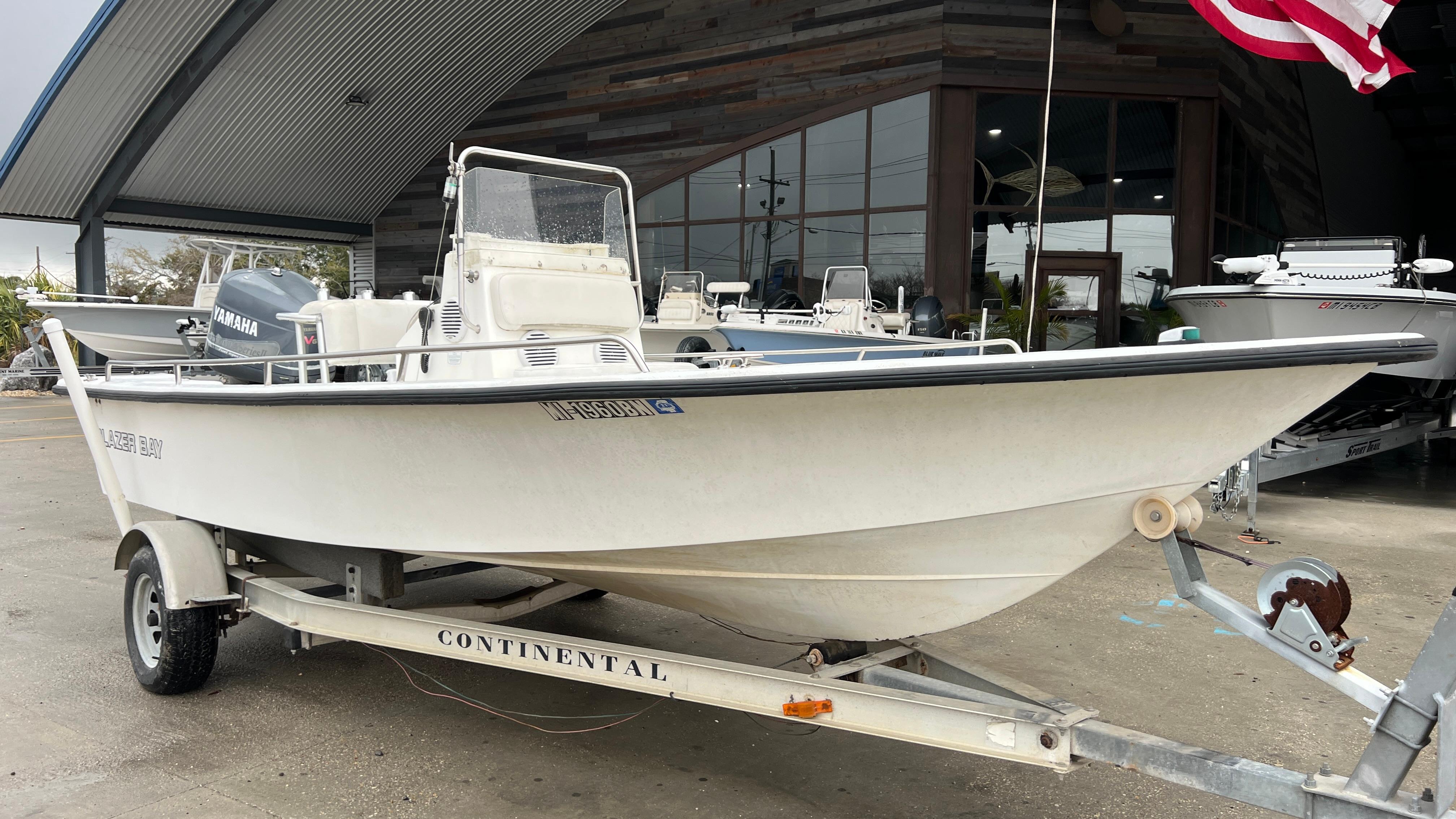 2000 Blazer 1860 boat on trailer, parked outside a building with an American flag.