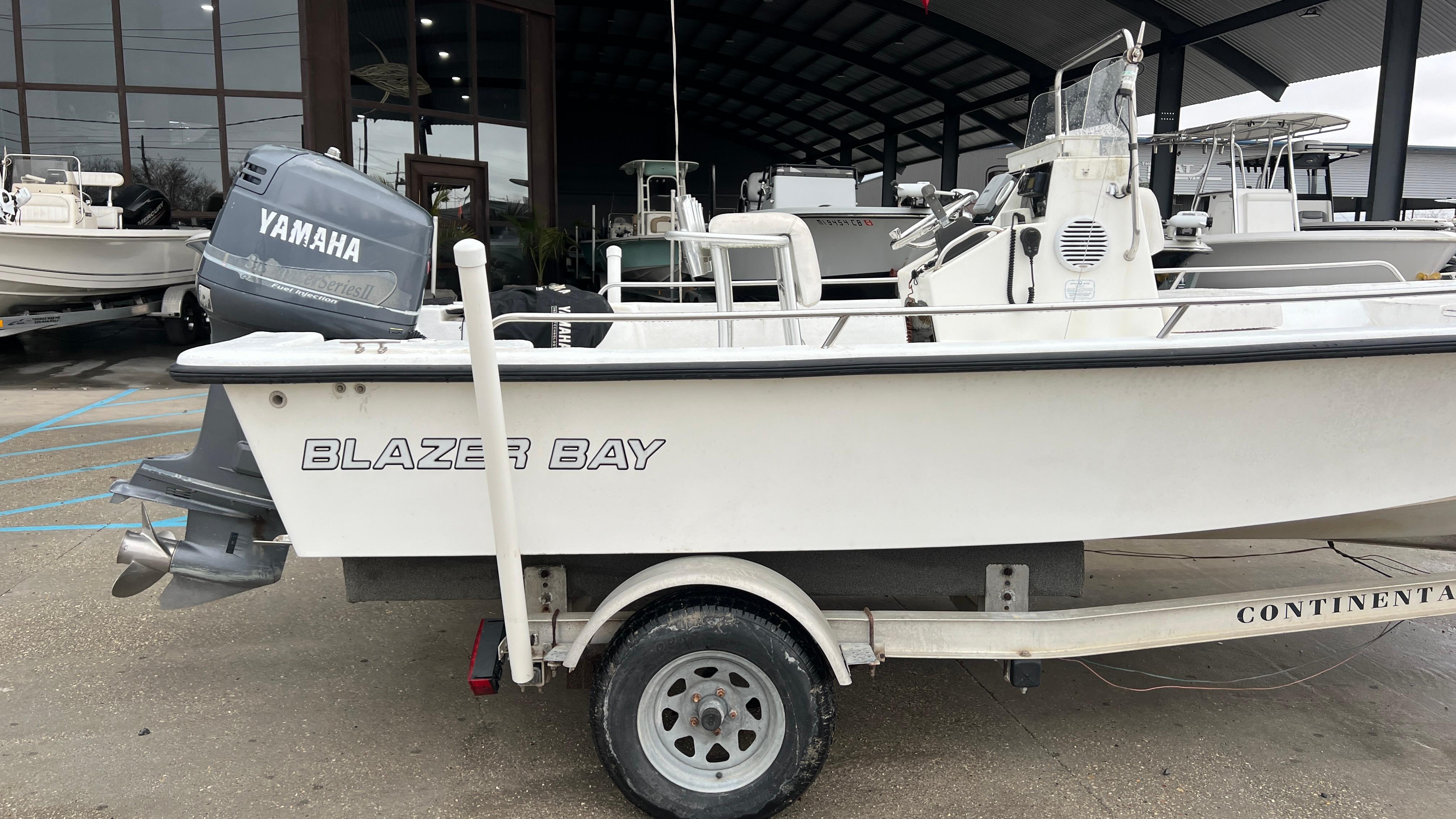 2000 Blazer 1860 boat with Yamaha motor on trailer, parked outside a showroom.