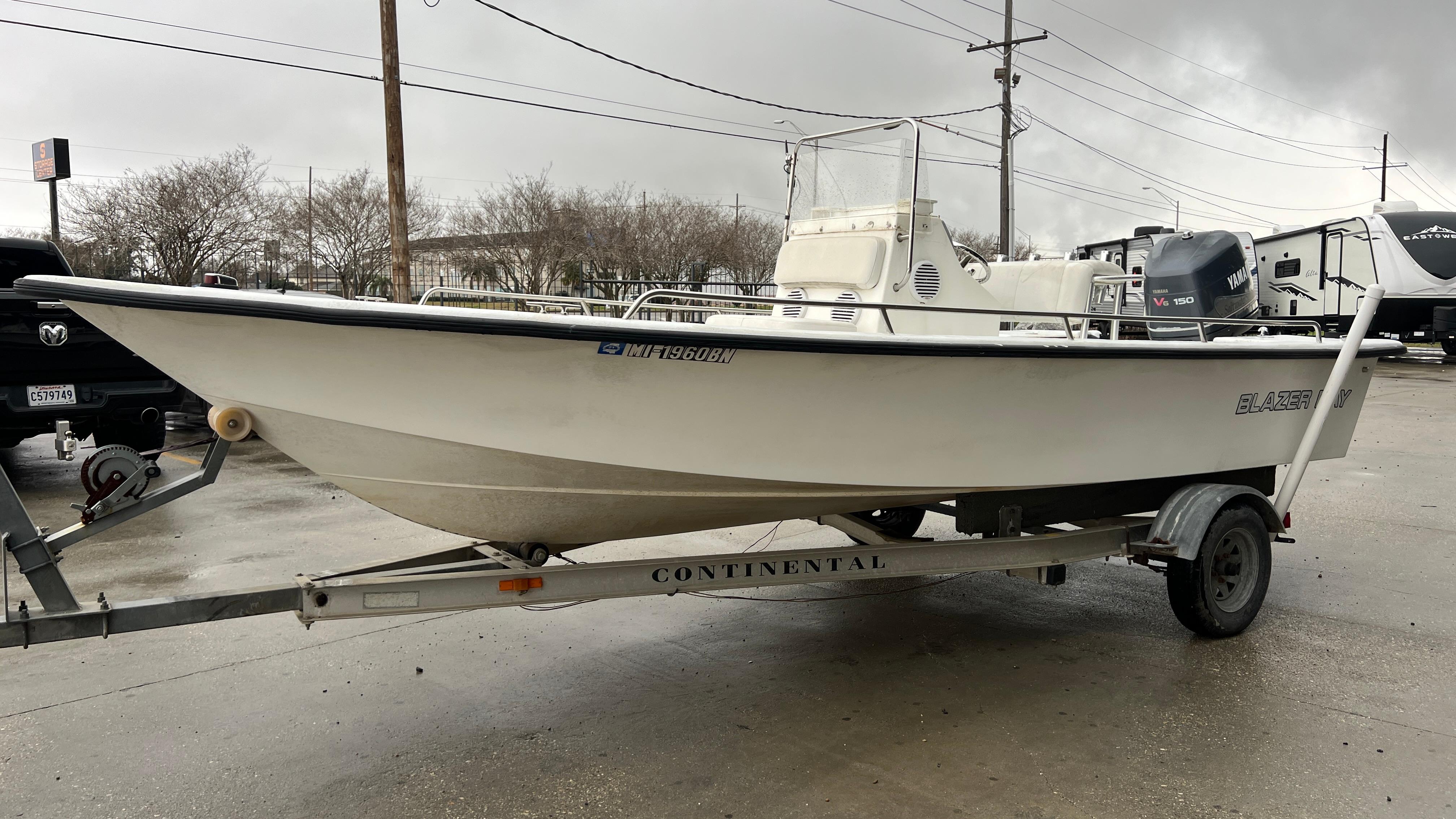 2000 Blazer 1860 boat on trailer, parked outdoors on a cloudy day.