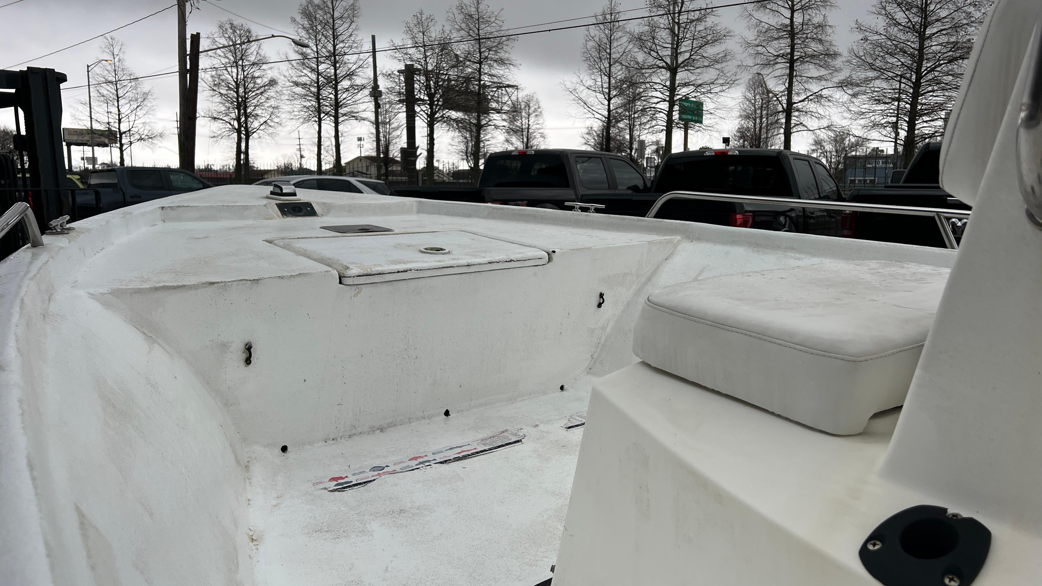 2000 Blazer 1860 boat deck with storage compartments, parked near trees and vehicles.