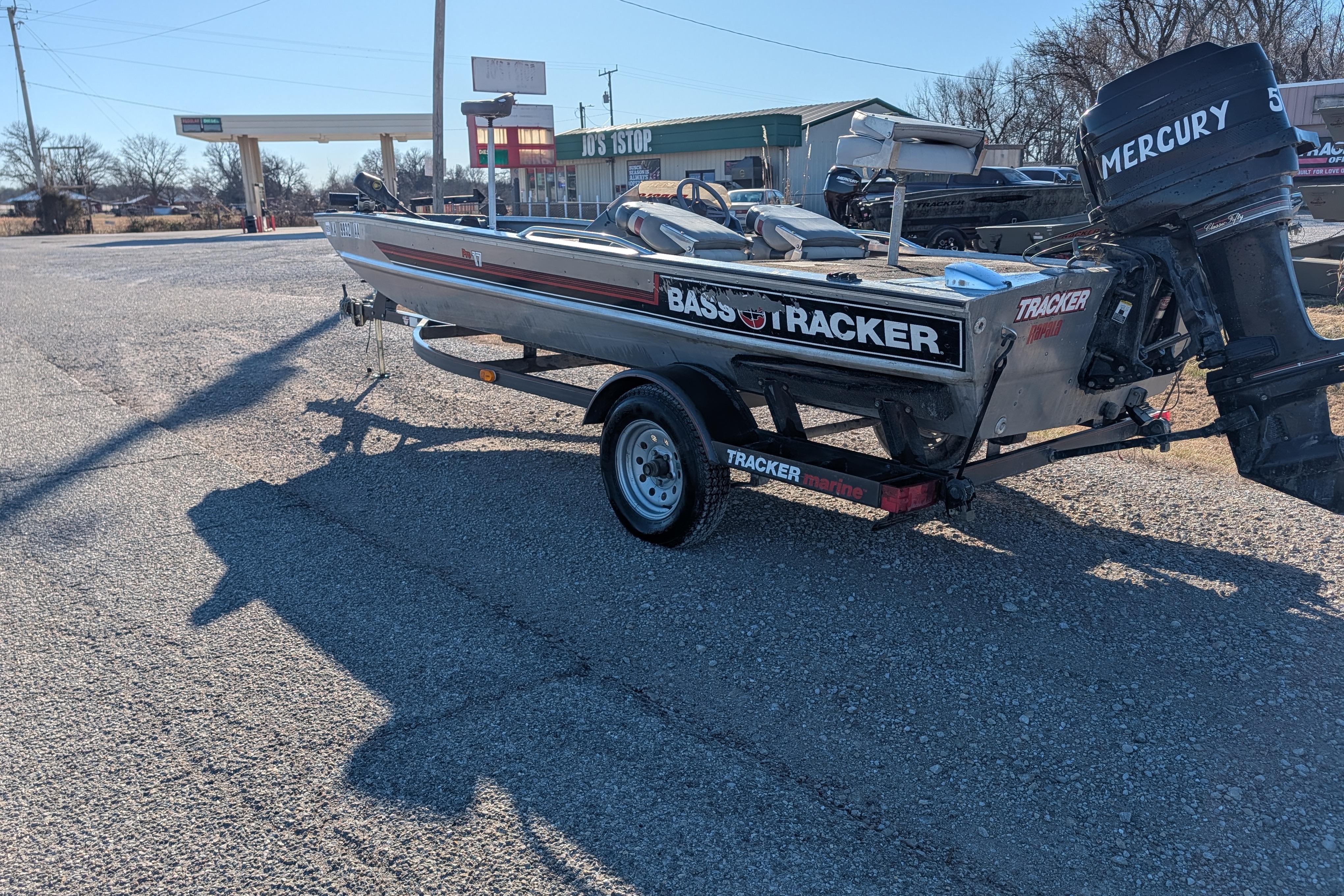 1988 Bass Tracker Pro 17 boat with Mercury engine on trailer in parking lot.