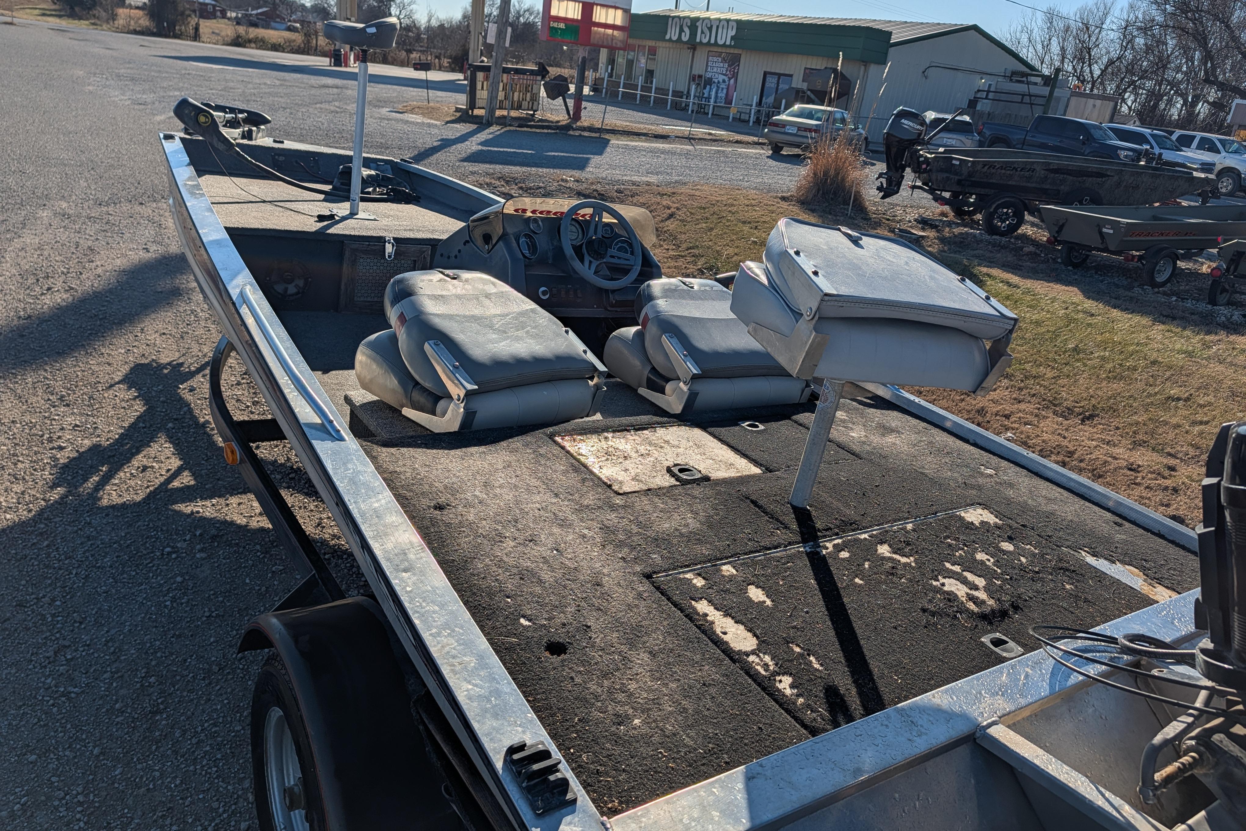 1988 Bass Tracker Pro 17 boat with worn seats and steering wheel, parked outdoors.
