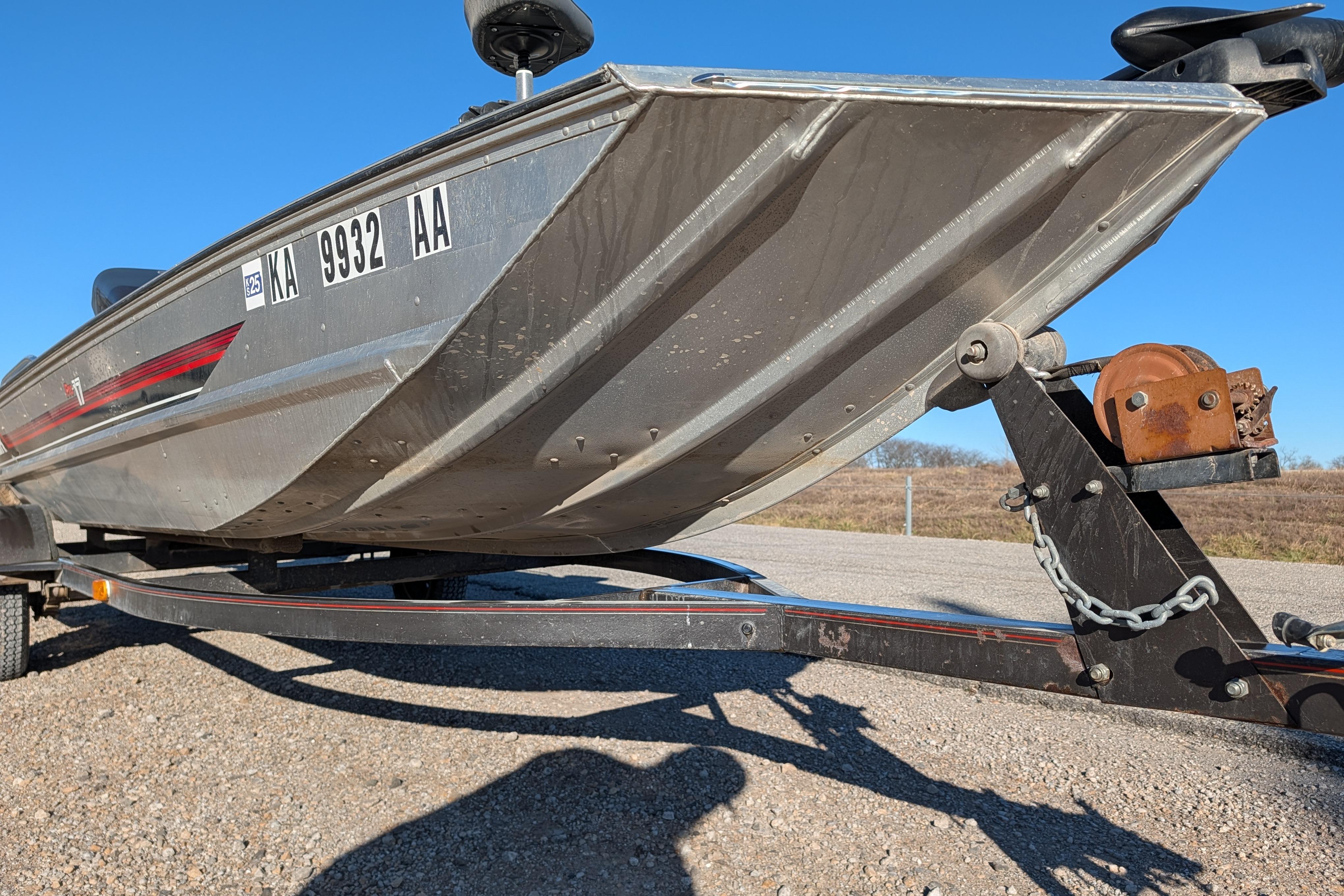 1988 Bass Tracker Pro 17 boat on trailer, sunny day, gravel surface.