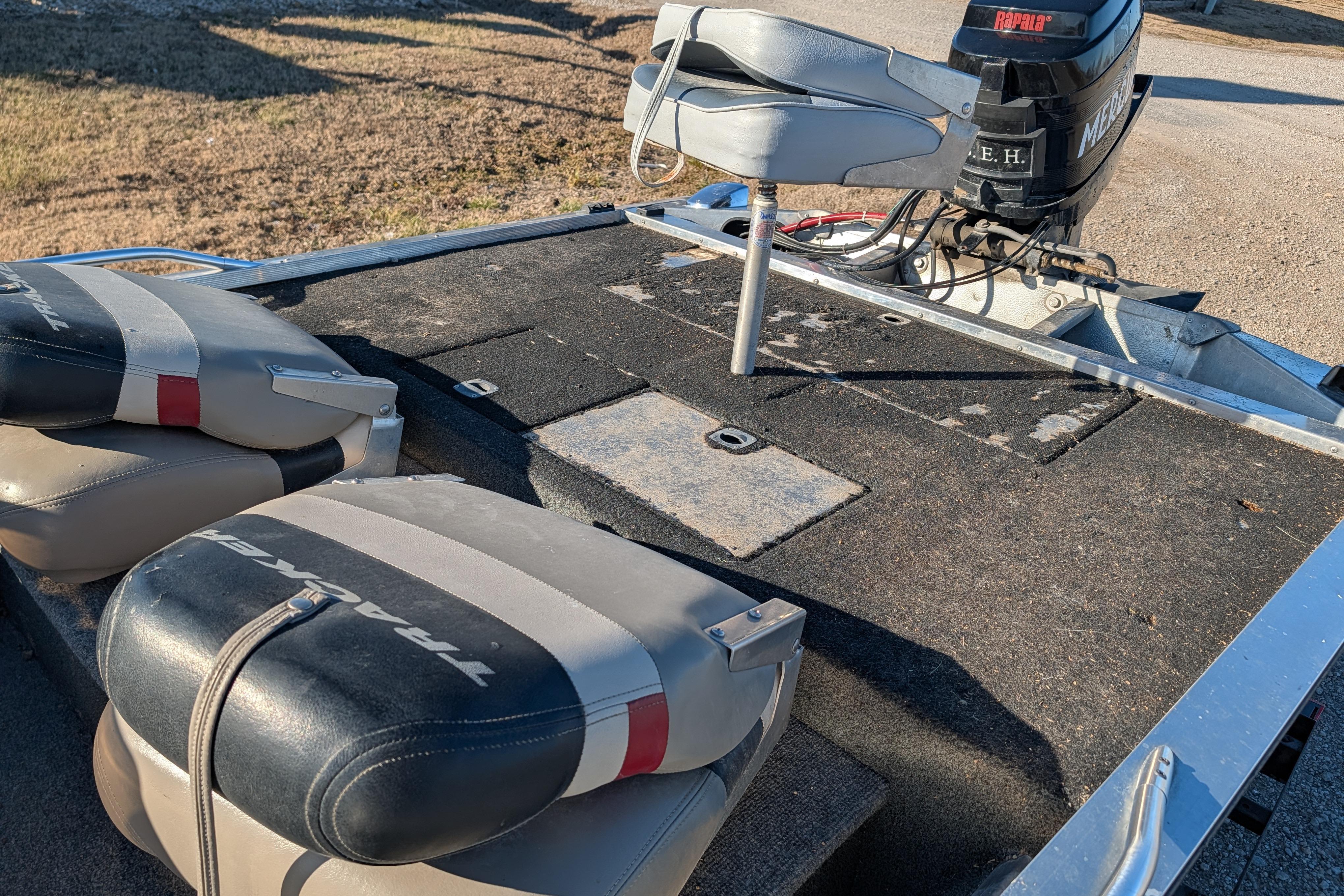 1988 Bass Tracker Pro 17 boat interior with seats and motor, showing wear and outdoor setting.