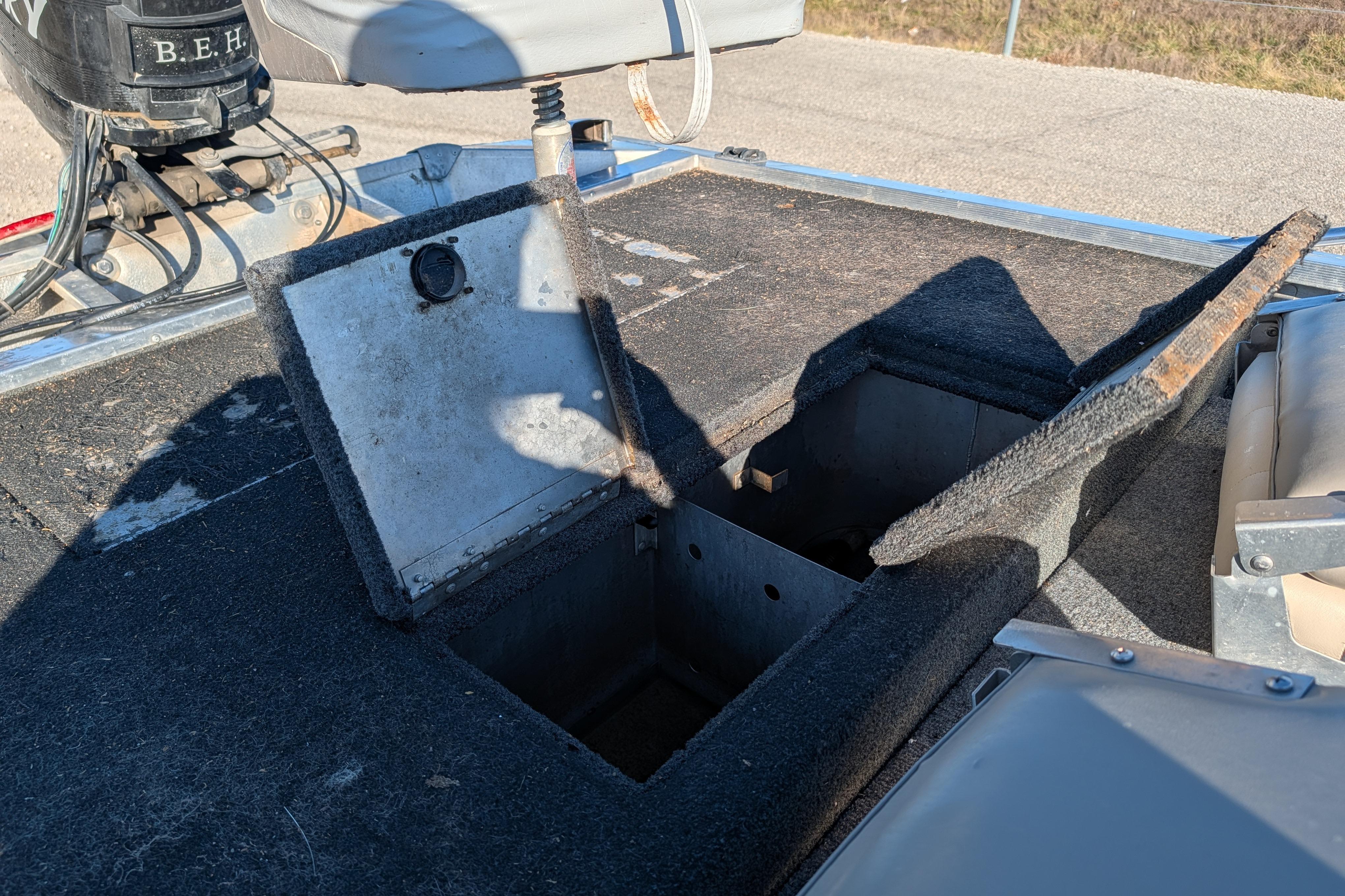 1988 Bass Tracker Pro 17 boat with open storage compartment and motor in view.