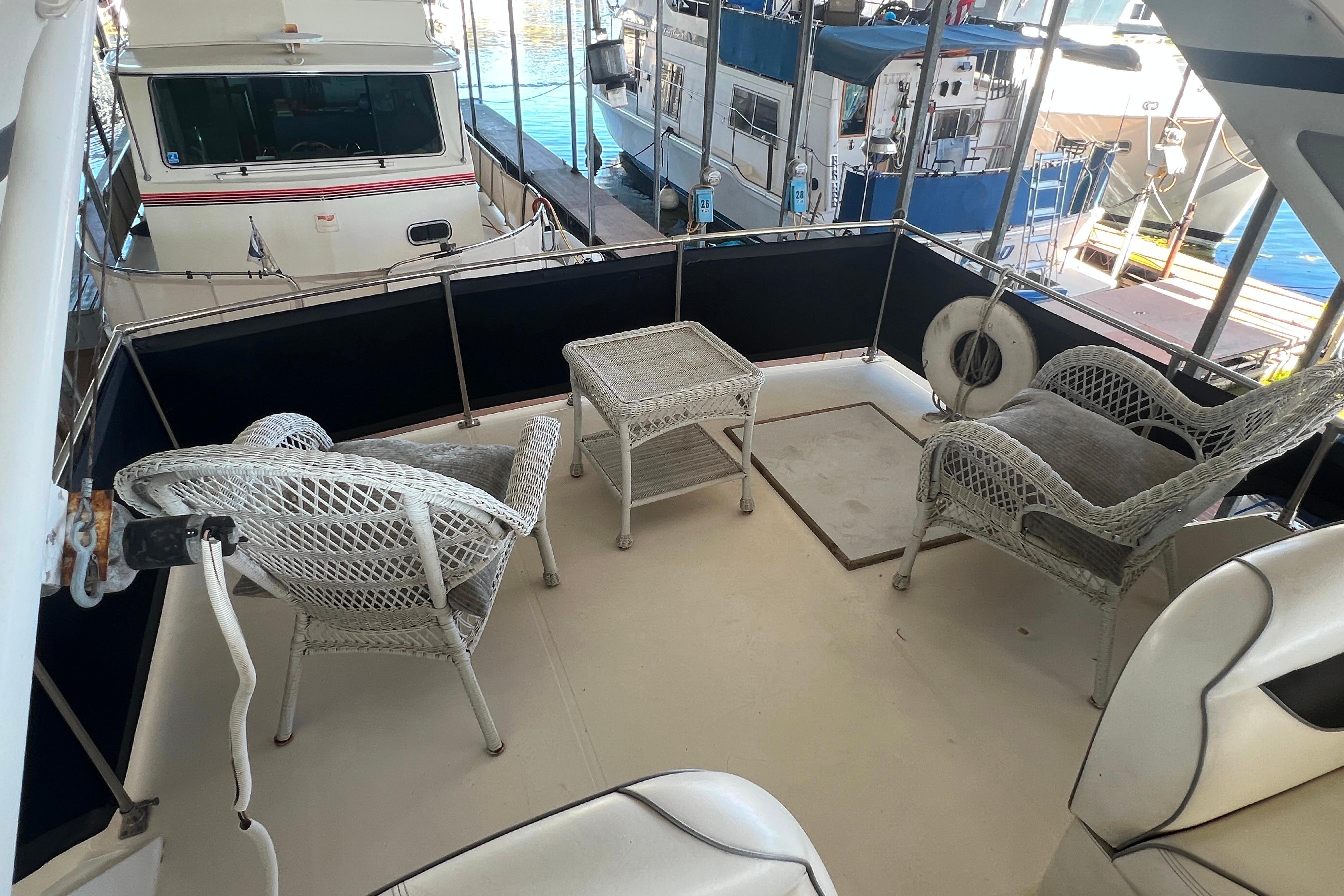 1986 Bayliner 4550 Motoryacht deck with wicker chairs and table, docked at marina.